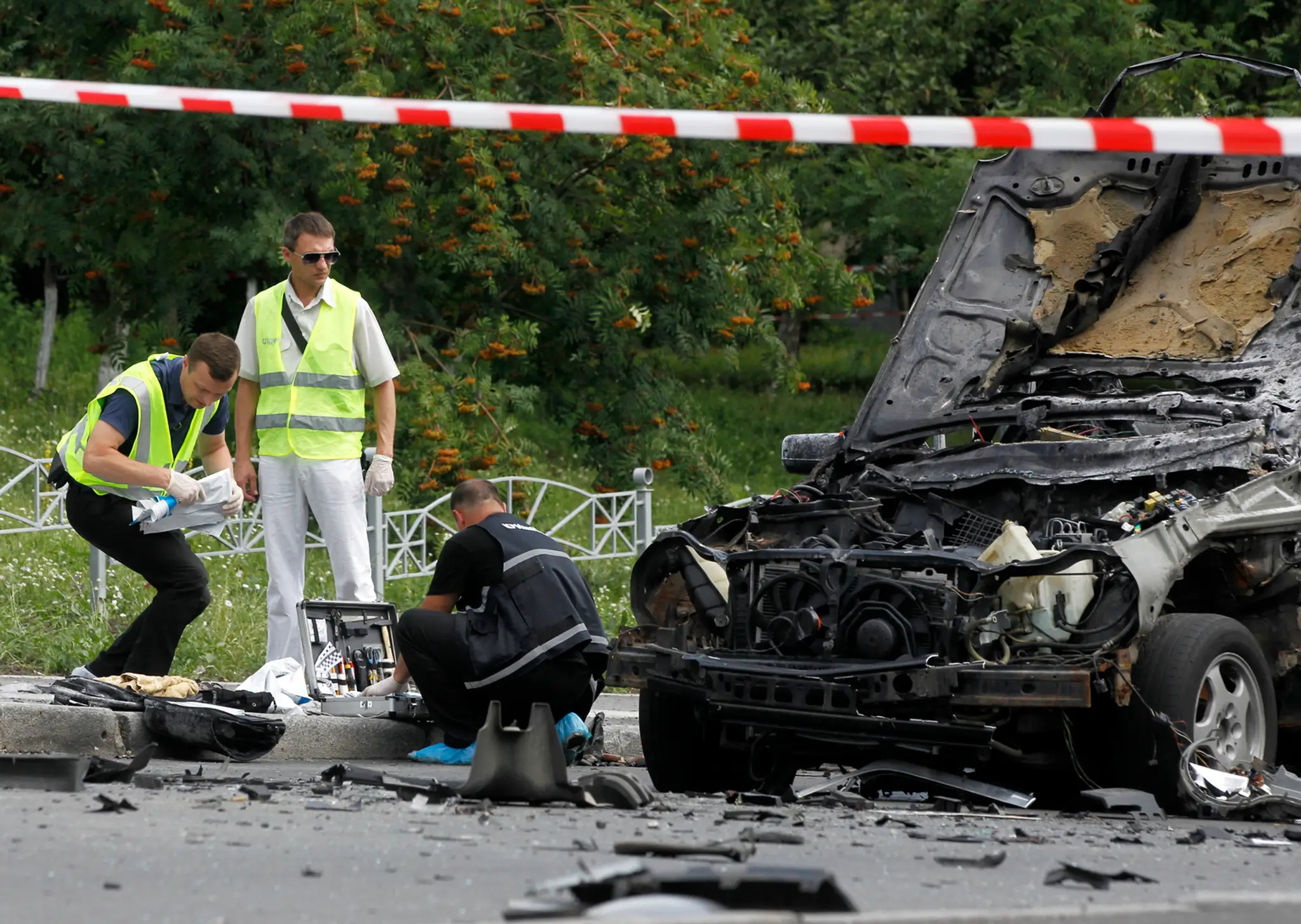 Forenzní experti prehľadávajú vrak automobilu.