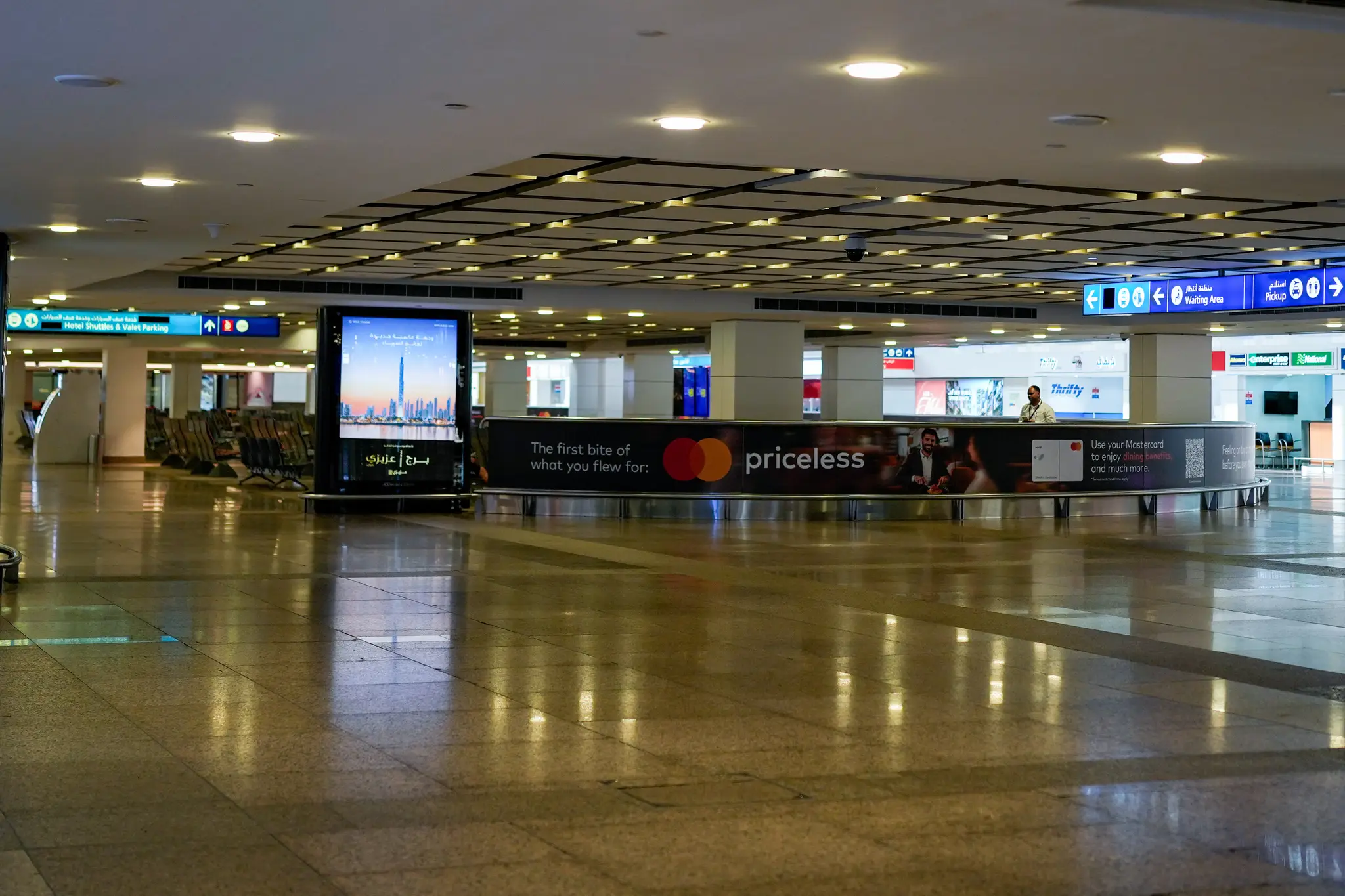 Pracovník je v prázdnej príletovej hale na medzinárdnom letisku v Dubaji.