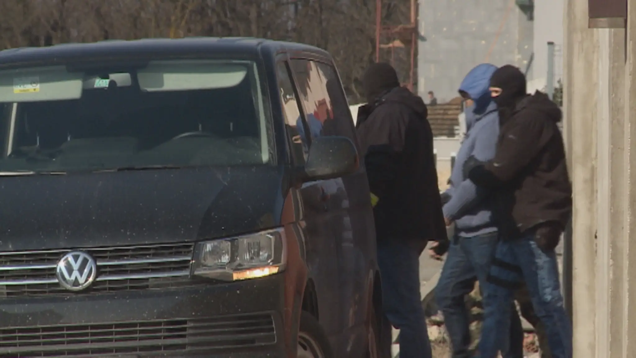 Policajti prevážajú mužov, zadržaných počas razií.