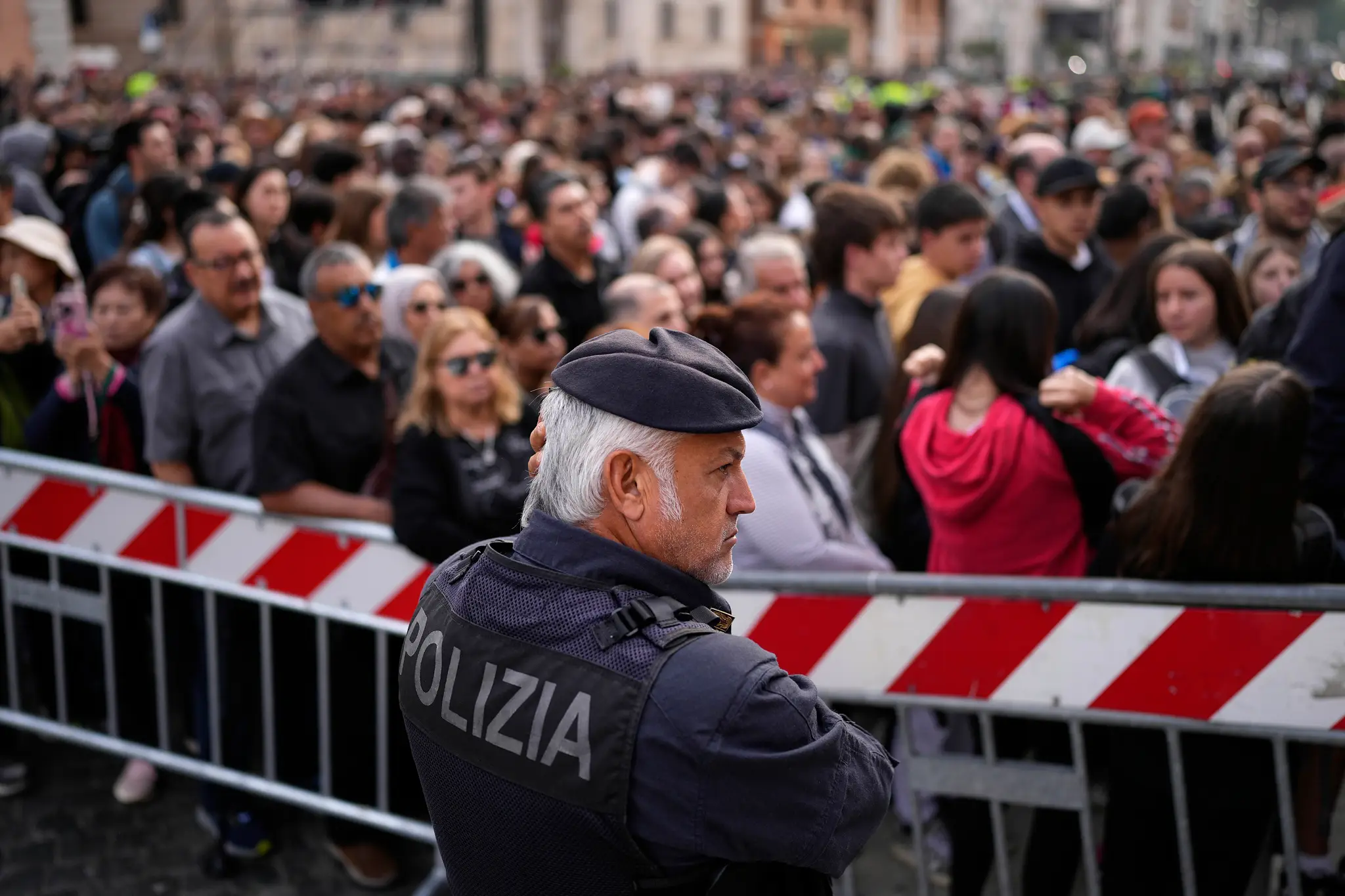 Policajt stojí vedľa ľudí, ktorí čakajú na vstup na Námestie svätého Petra, aby vzdali úctu zosnulému pápežovi Františkovi.