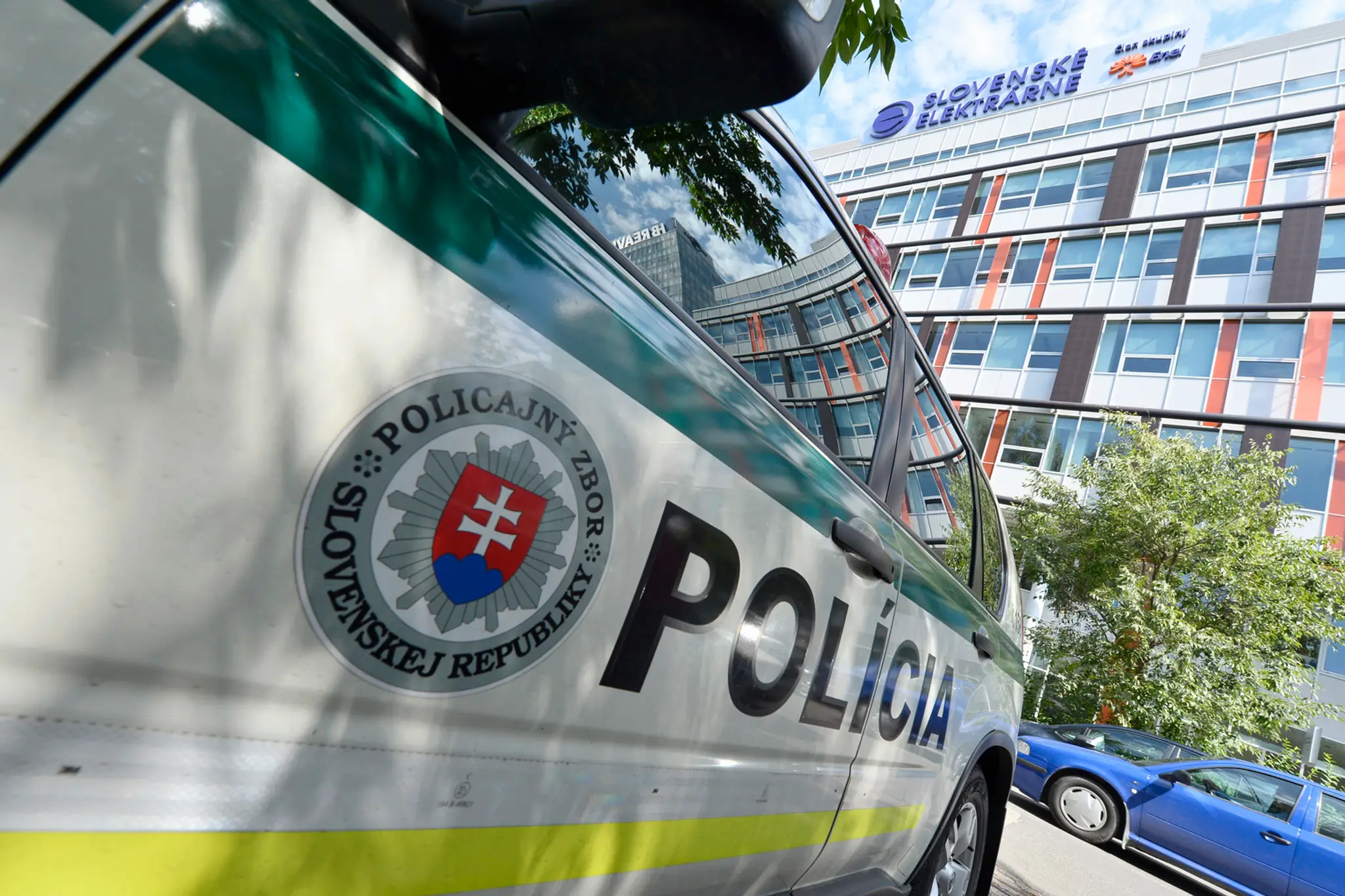 Policajné auto stojí počas razie pred budovou spoločnosti Slovenské elektrárne.