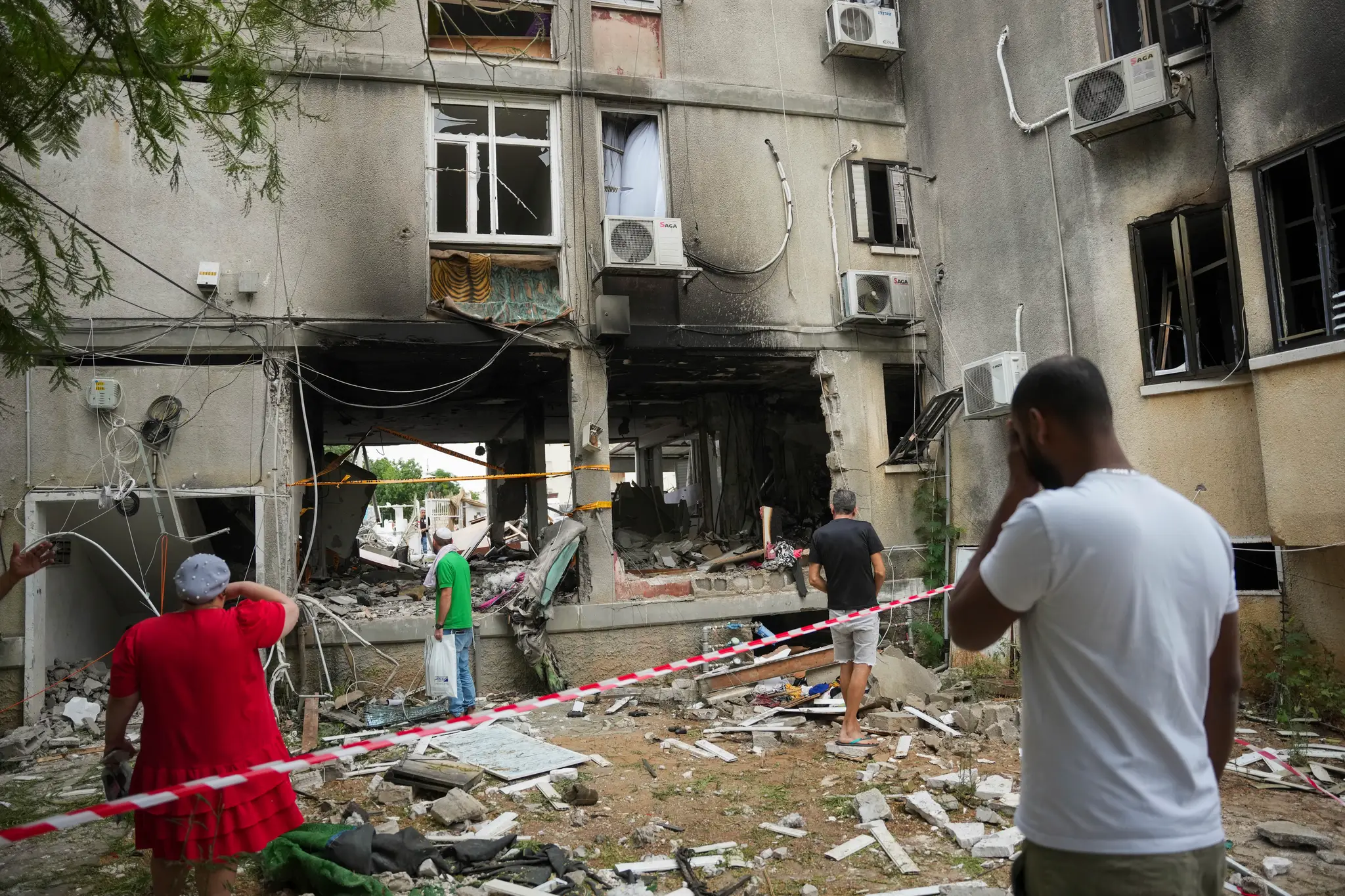 Izraelčania kontrolujú poškodenú obytnú budovu po zásahu raketou vypálenou z pásma Gazy v meste Aškelon.
