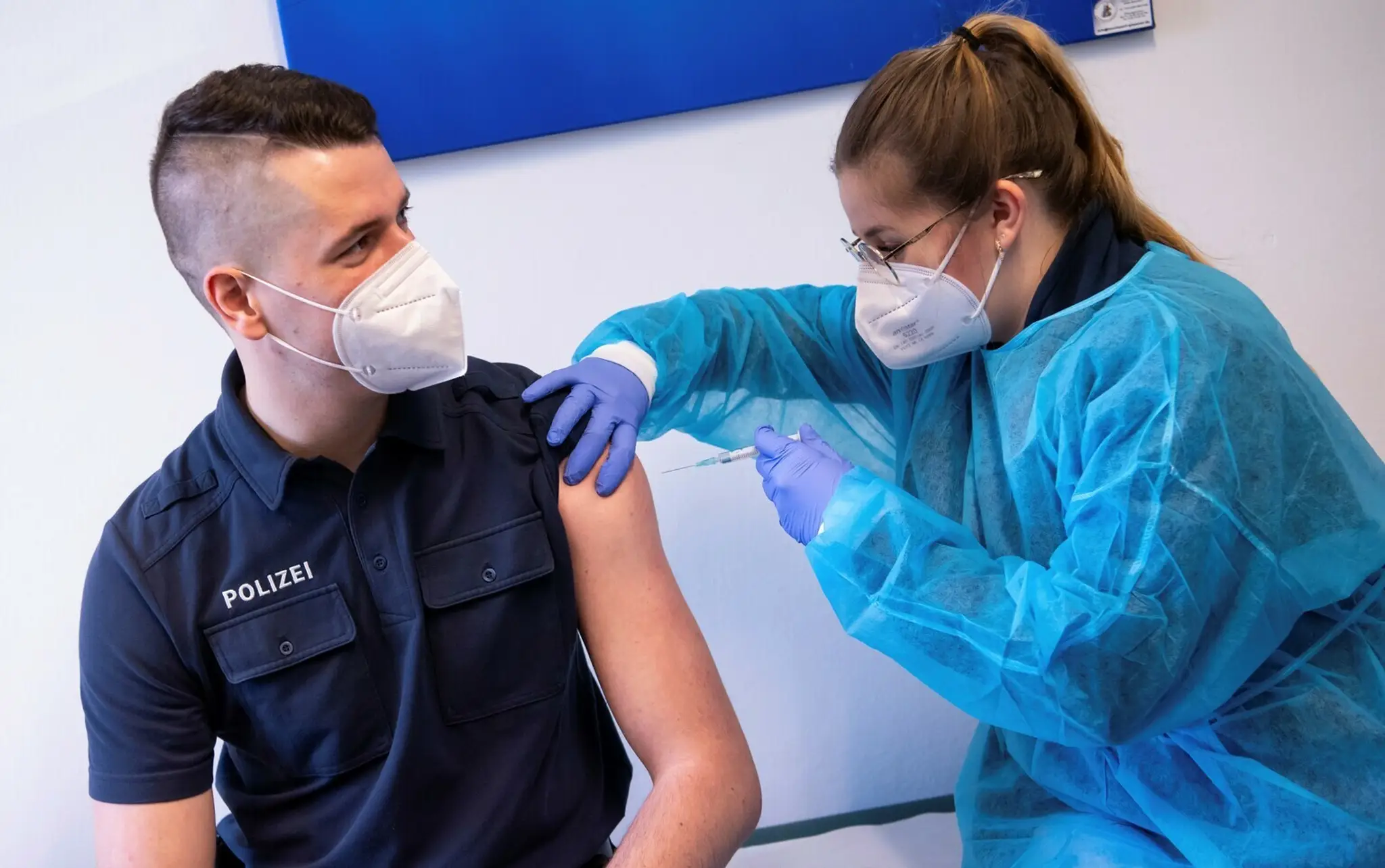 Zdravotníčka podáva vakcínu proti ochoreniu COVID-19 od spoločnosti AstraZeneca policajtovi.