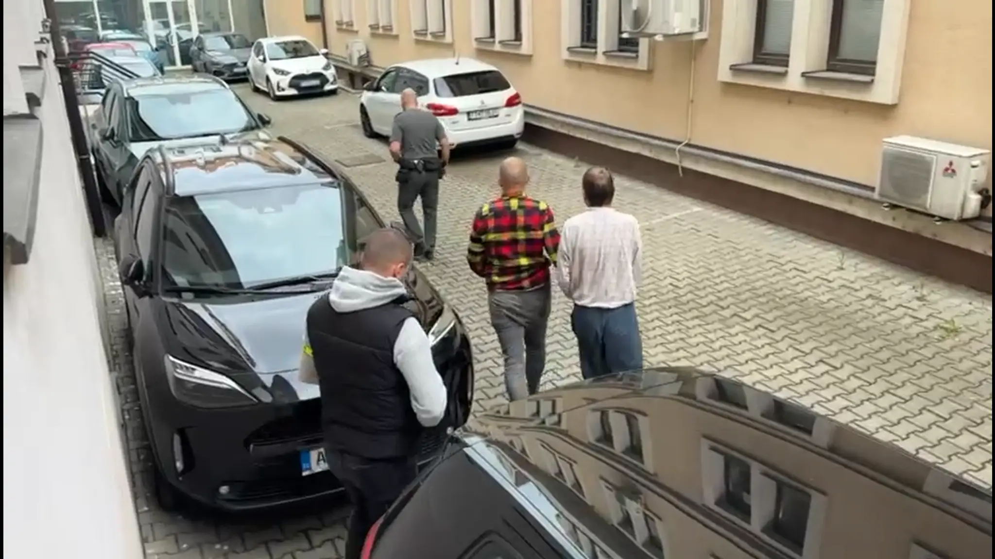 Na snímke otec, ktorý zavraždil syna. V putách ho odvážajú do väzby.