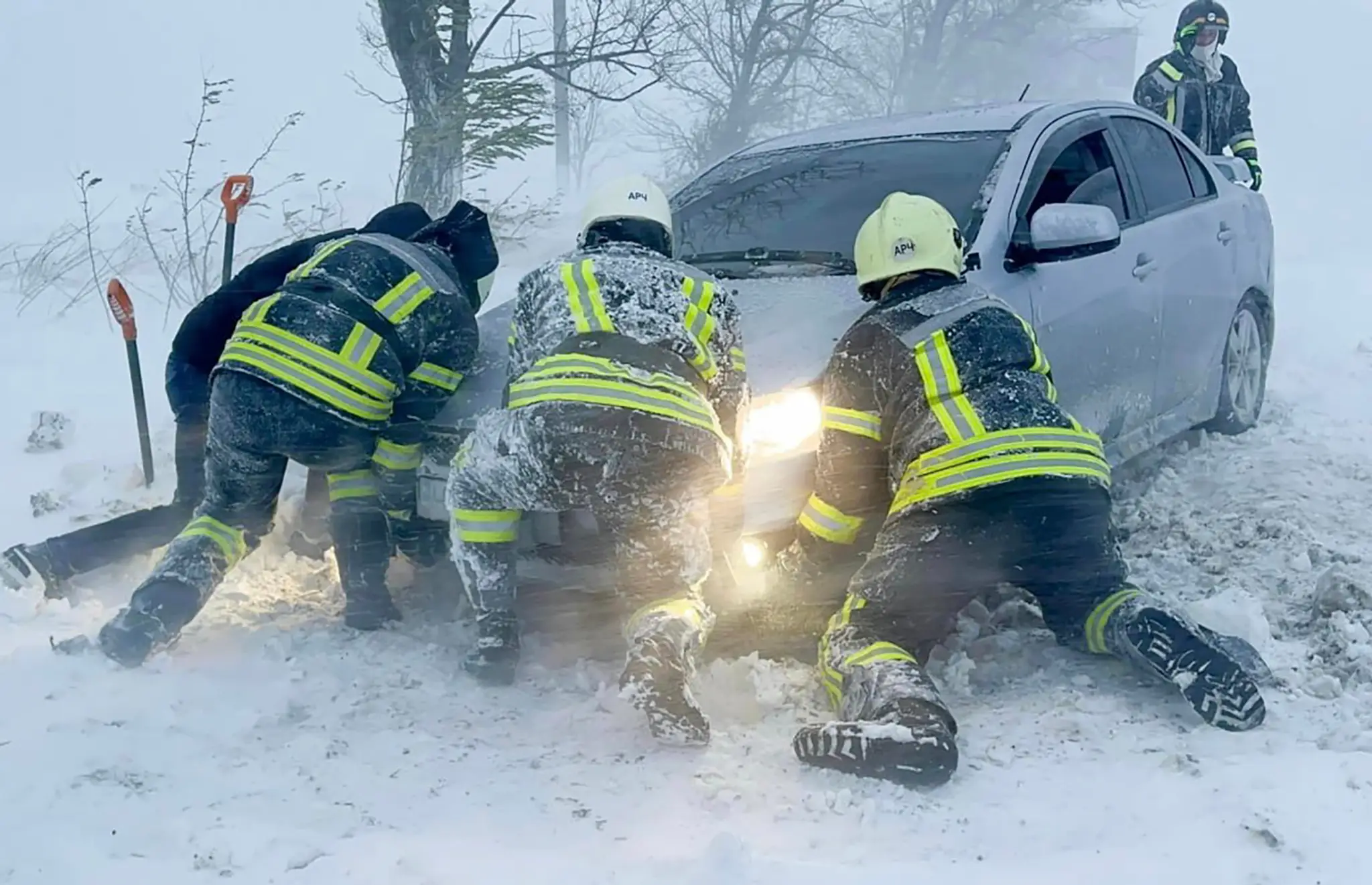 Ukrajinskí záchranári snažia odtlačiť auto, ktoré uviazlo na ceste počas snehovej víchrice v Odeskej oblasti.