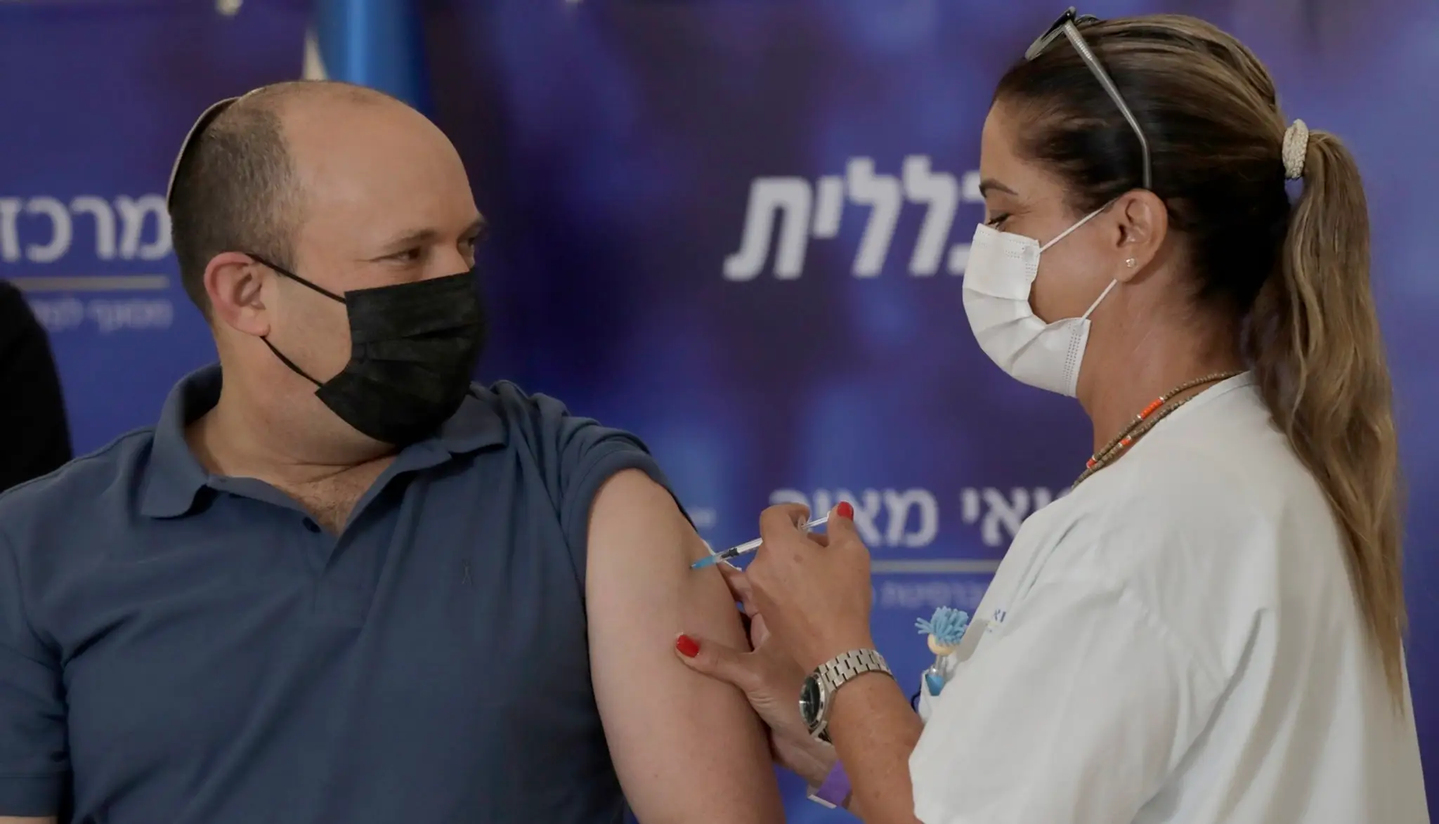 Izraelský premiér Naftali Bennett dostáva posilňovaciu dávku vakcínu proti ochoreniu COVID-19 v nemocnici v meste Kfar Saba.