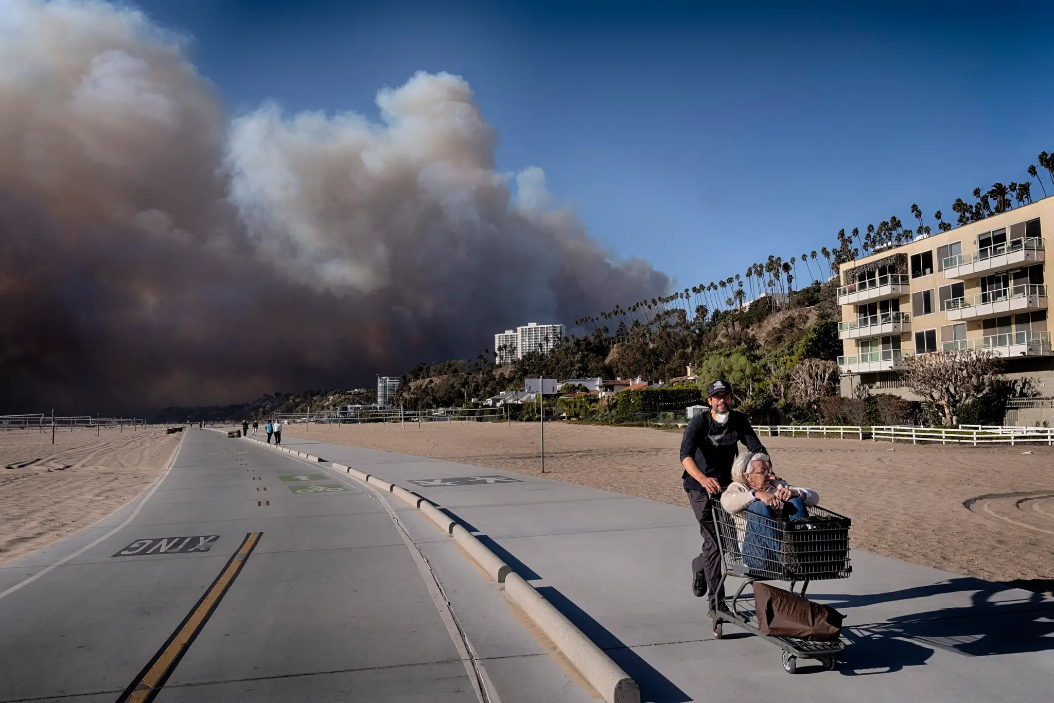 Na snímke ľudia, ktorí utekajú pred požiarom v Los Angeles.