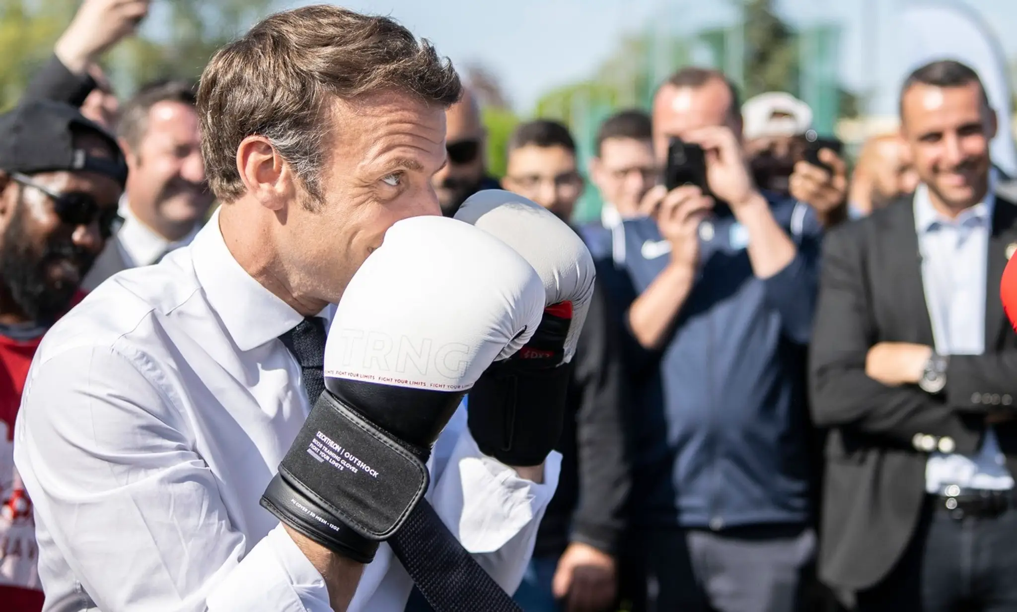 Francúzsky prezident Emmanuel Macron sparuje so žiakom školy boxu na archívnej snímke z apríla 2022.