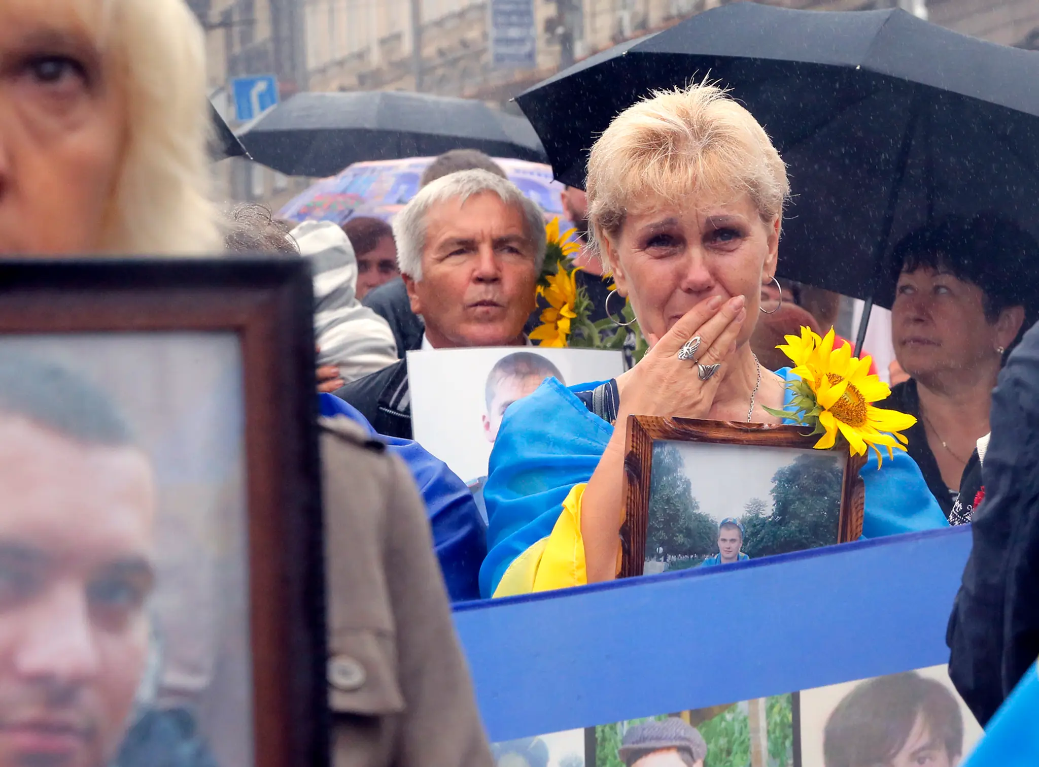 Ľudia držia fotografie svojich príbuzných, ktorí ako vojaci zahynuli počas konfliktu so separatistami.