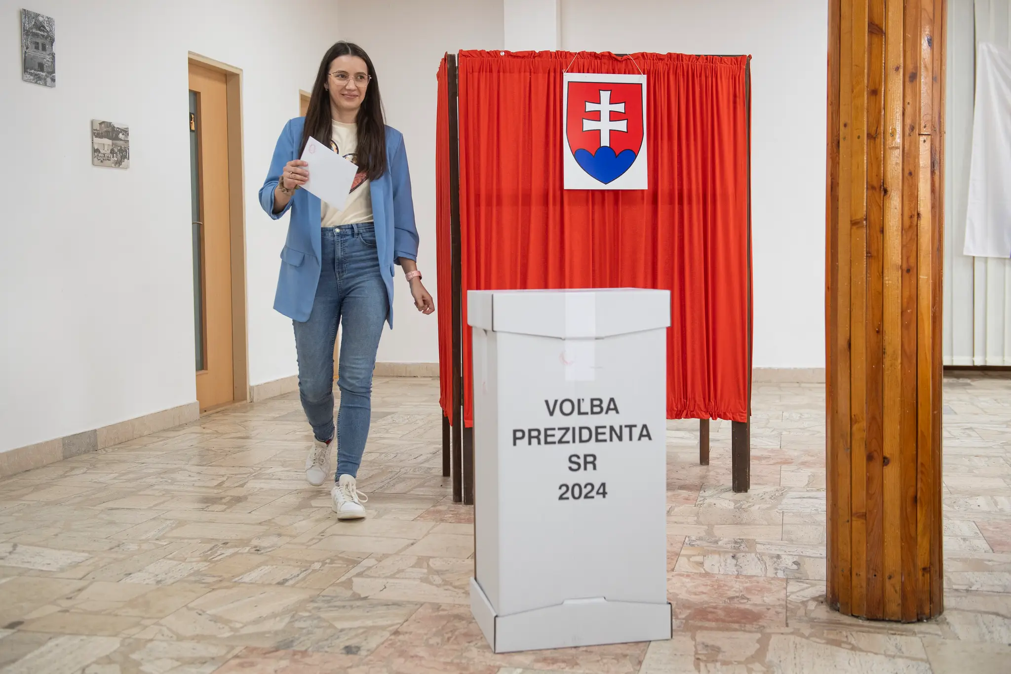 Na snímke volička prichádza k volebnej schránke počas hlasovania.