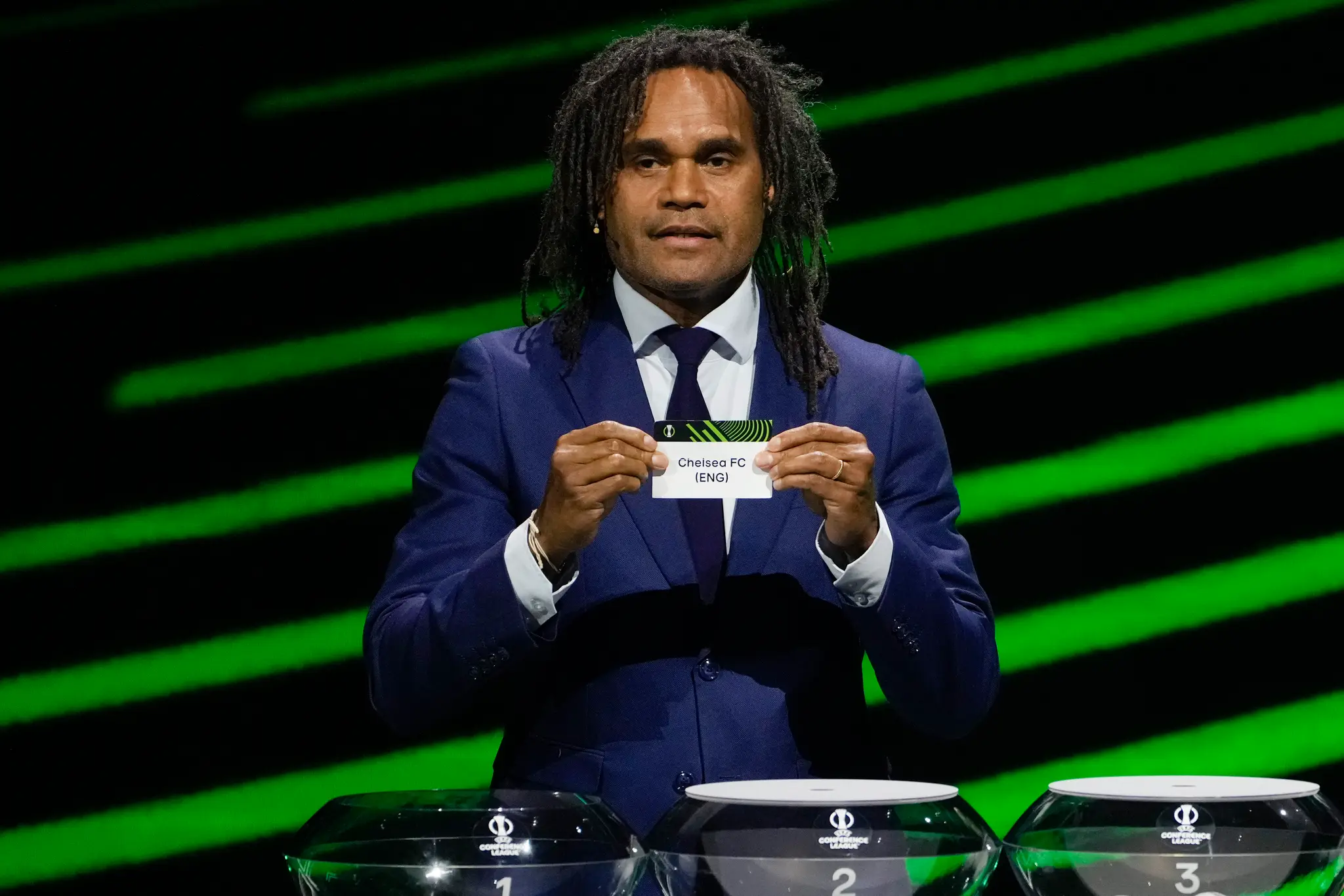 Na snímke bývalý francúzsky futbalista Christian Karembeu ukazuje lístok s nápisom FC Chelsea počas žrebu skupinovej fázy Európskej konferenčnej ligy v Monaku.