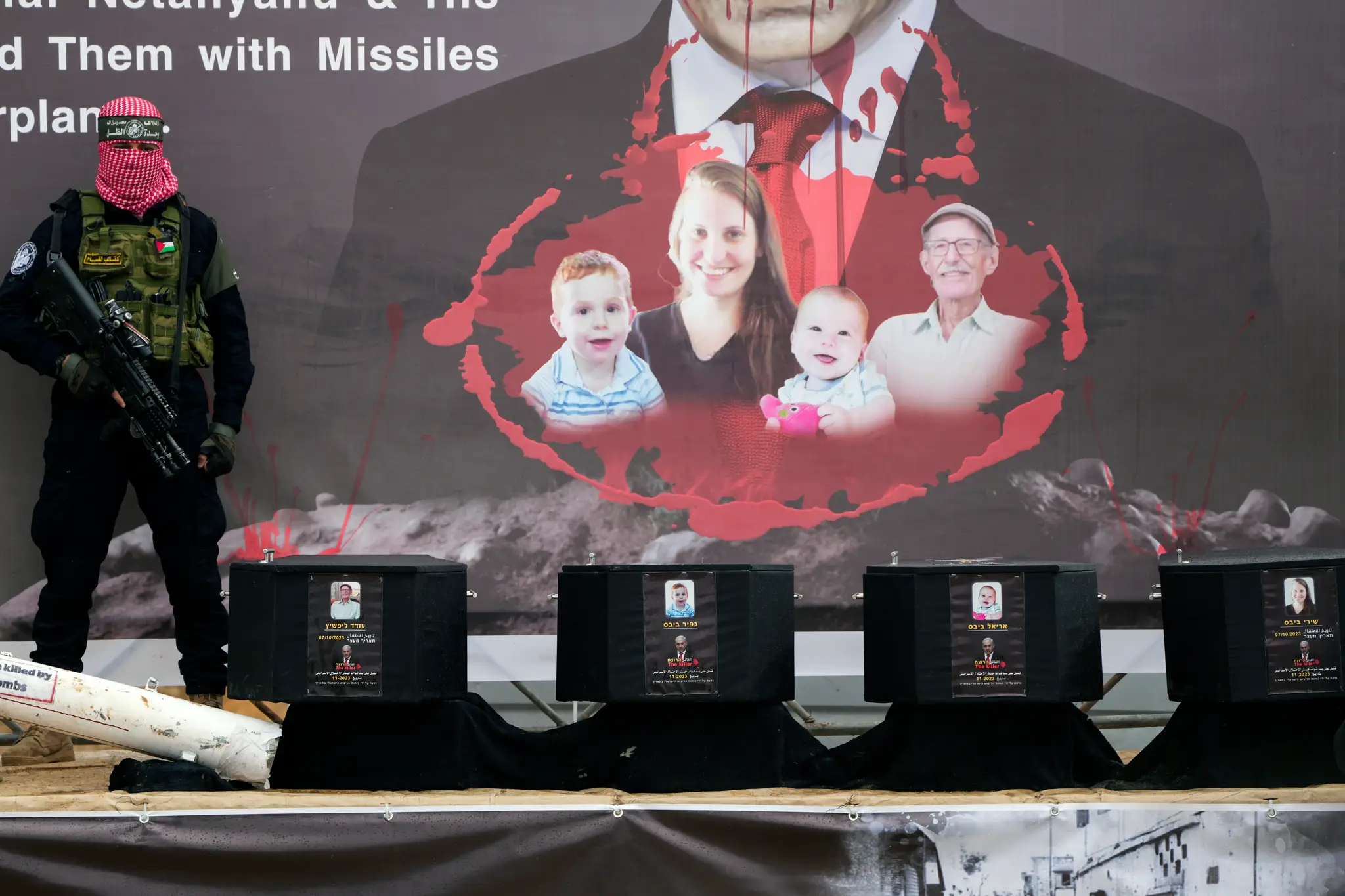 Na snímke palestínsky bojovník stojí pri rakvách s telesnými pozostatkami štyroch izraelských rukojemníkov počas odovzdania ich tiel.