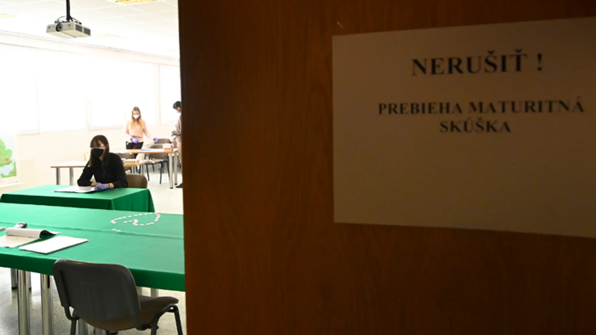 Študentka v ochrannom rúšku odpovedá počas ústnej maturitnej skúšky.