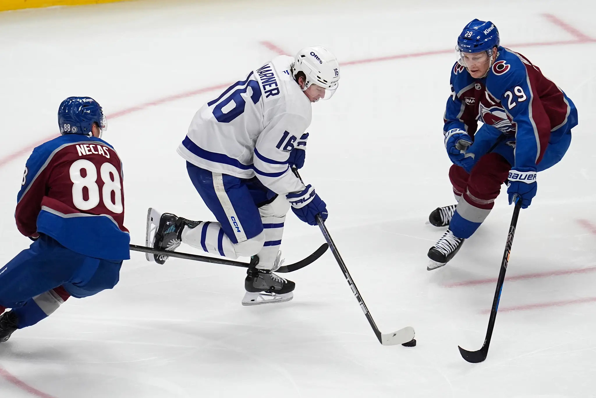 Na snímke hokejista Toronta Mitch Marner (uprostred), hráči Colorada Martin Nečas (vľavo) a Nathan MacKinnon (vpravo).