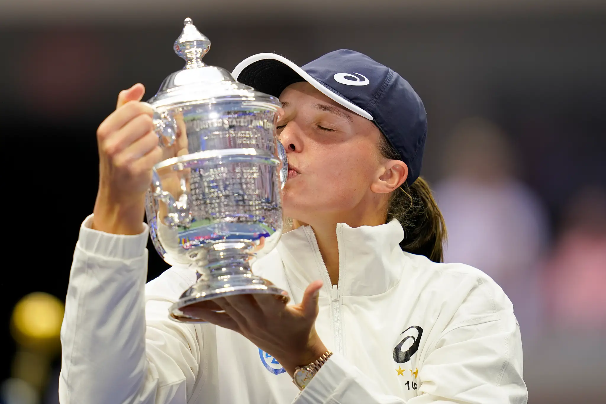 Poľská tenistka Iga Swiateková bozkáva trofej pre víťazku US Open po výhre  nad Tunisankou Ons Jabeurovou 6:2, 7:6.