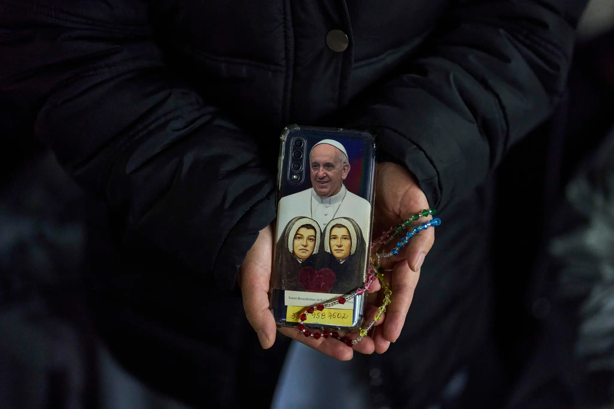 Mníška ukazuje zadný kryt svojho mobilného telefónu s fotografiou pápeža Františka počas večerného modlenia ruženca za jeho zdravie na Námestí sv. Petra.