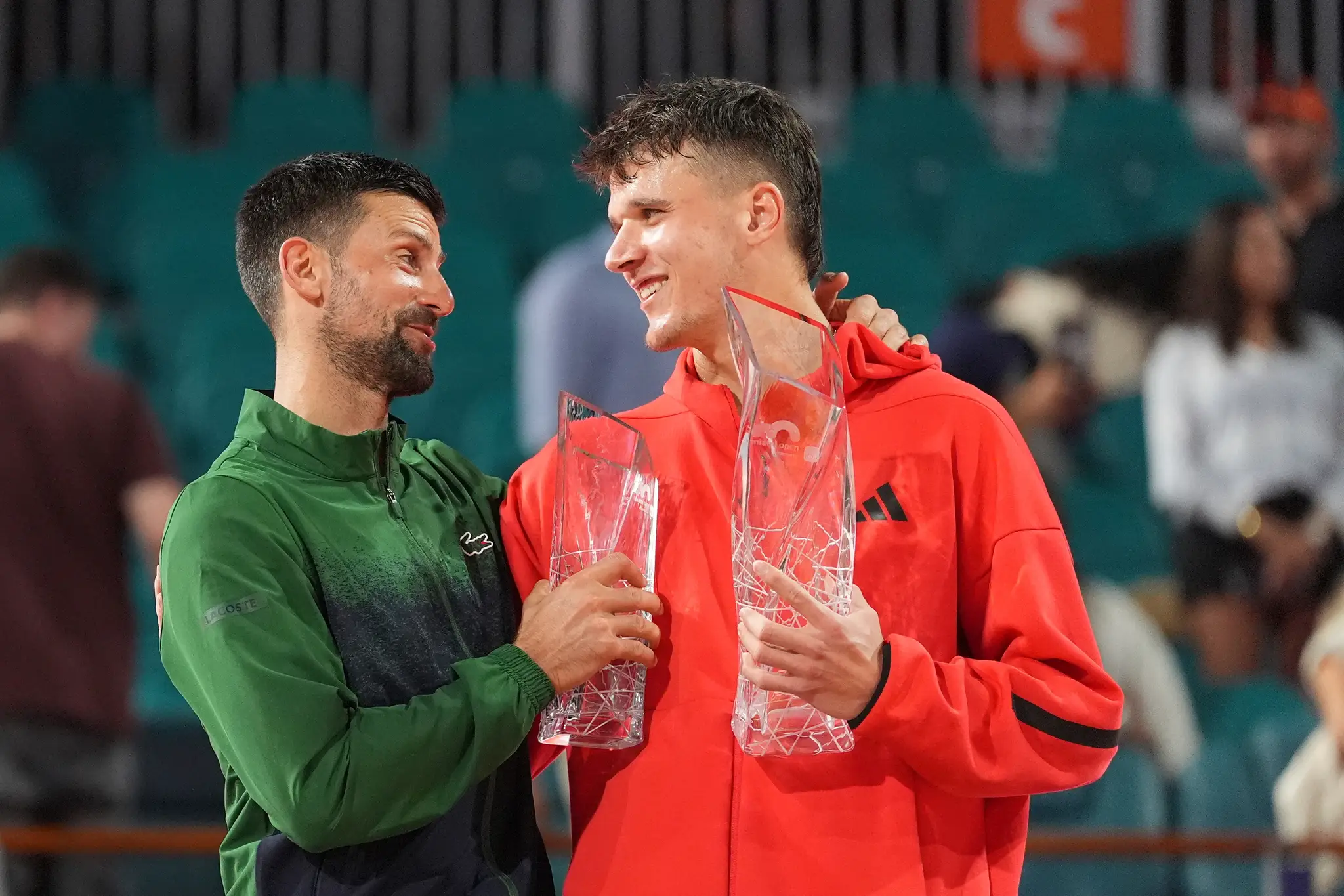 Český tenista Jakub Menšík drží trofej po triumfe nad Novakom Djokovičom (vľavo).