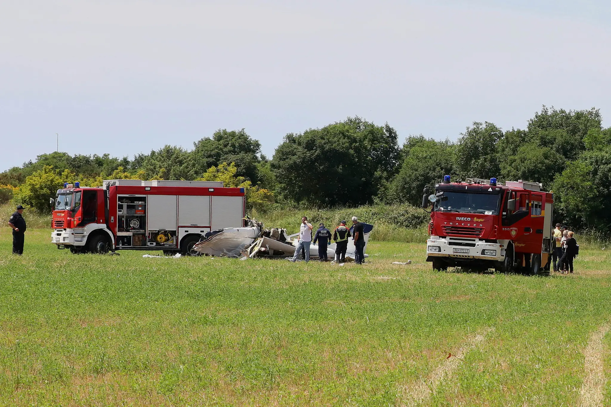 Na snímke policajti a hasiči si prezerajú vrak malého lietadla, ktoré havarovalo neďaleko obľúbeného prímorského letoviska Medulin.