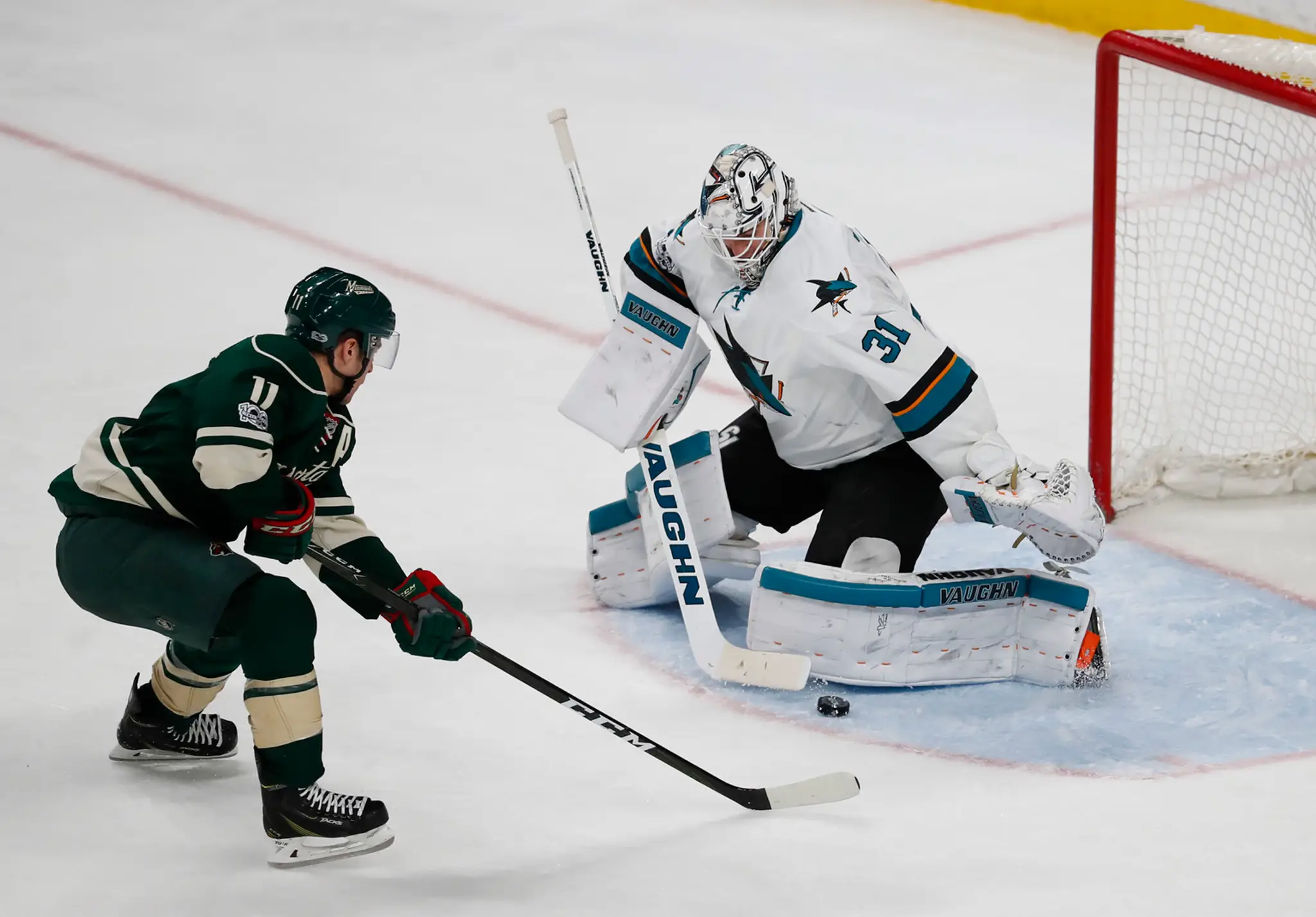 Gólman San Jose Martin Jones (vpravo) čelí Zachovi Parisemu z Minnesoty v dueli NHL.