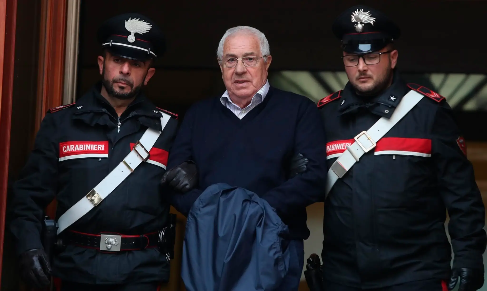 Policajti eskortujú  údajného bossa sicílskej mafie Cosa Nostra Settimo Minea, ktorého zatkli v palerme.