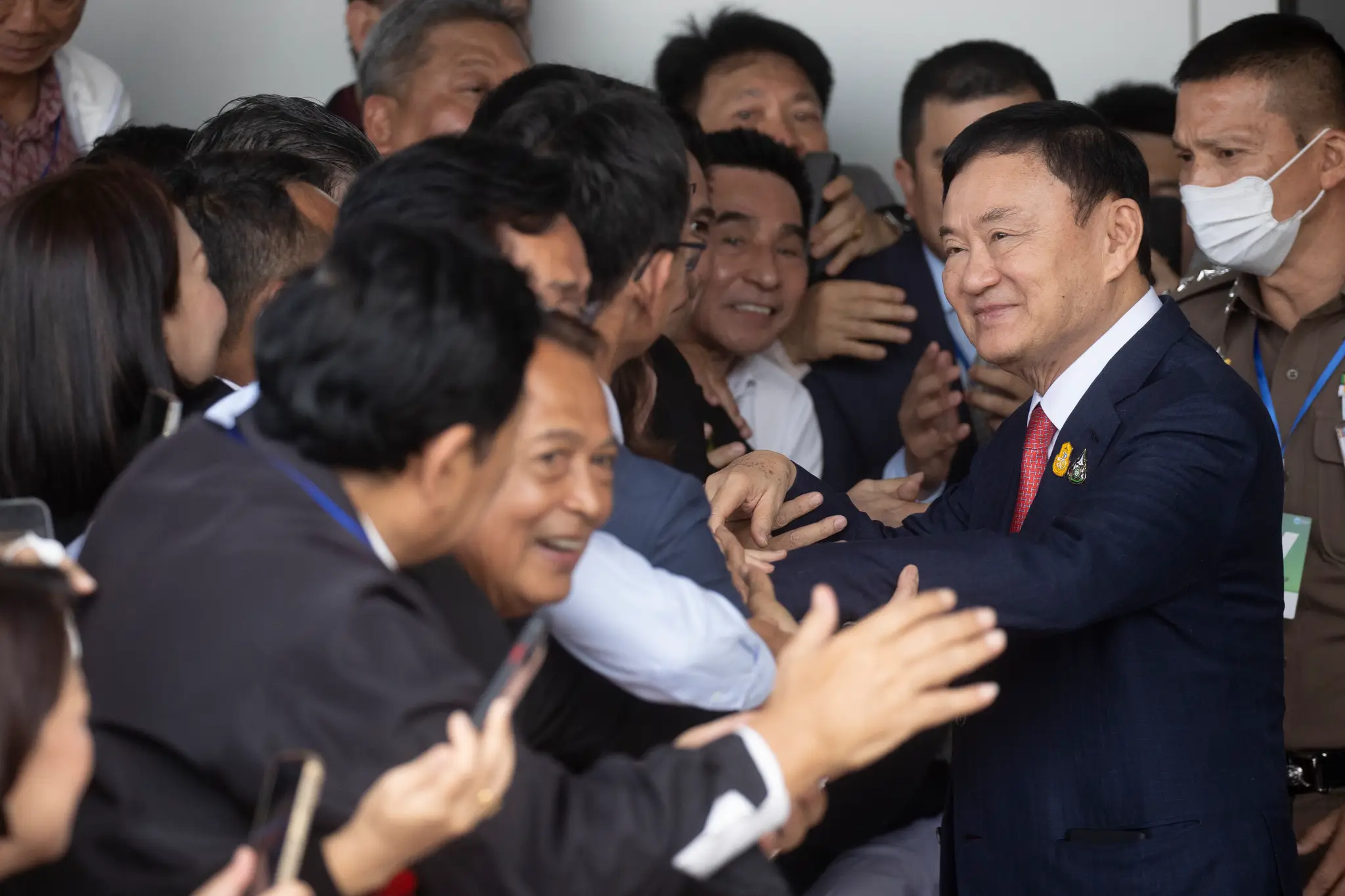 Bývalý thajský premiér Thaksin Šinavatra sa zdraví s priaznivcami počas príchodu na letisko v Bangkoku.