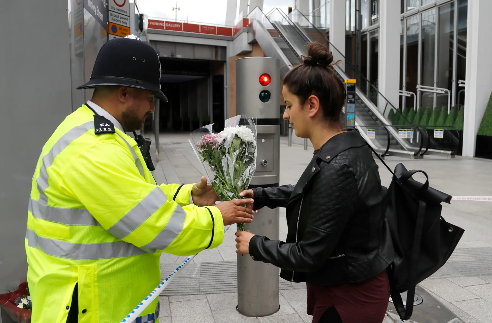 Žena podáva policajtovi kvety.