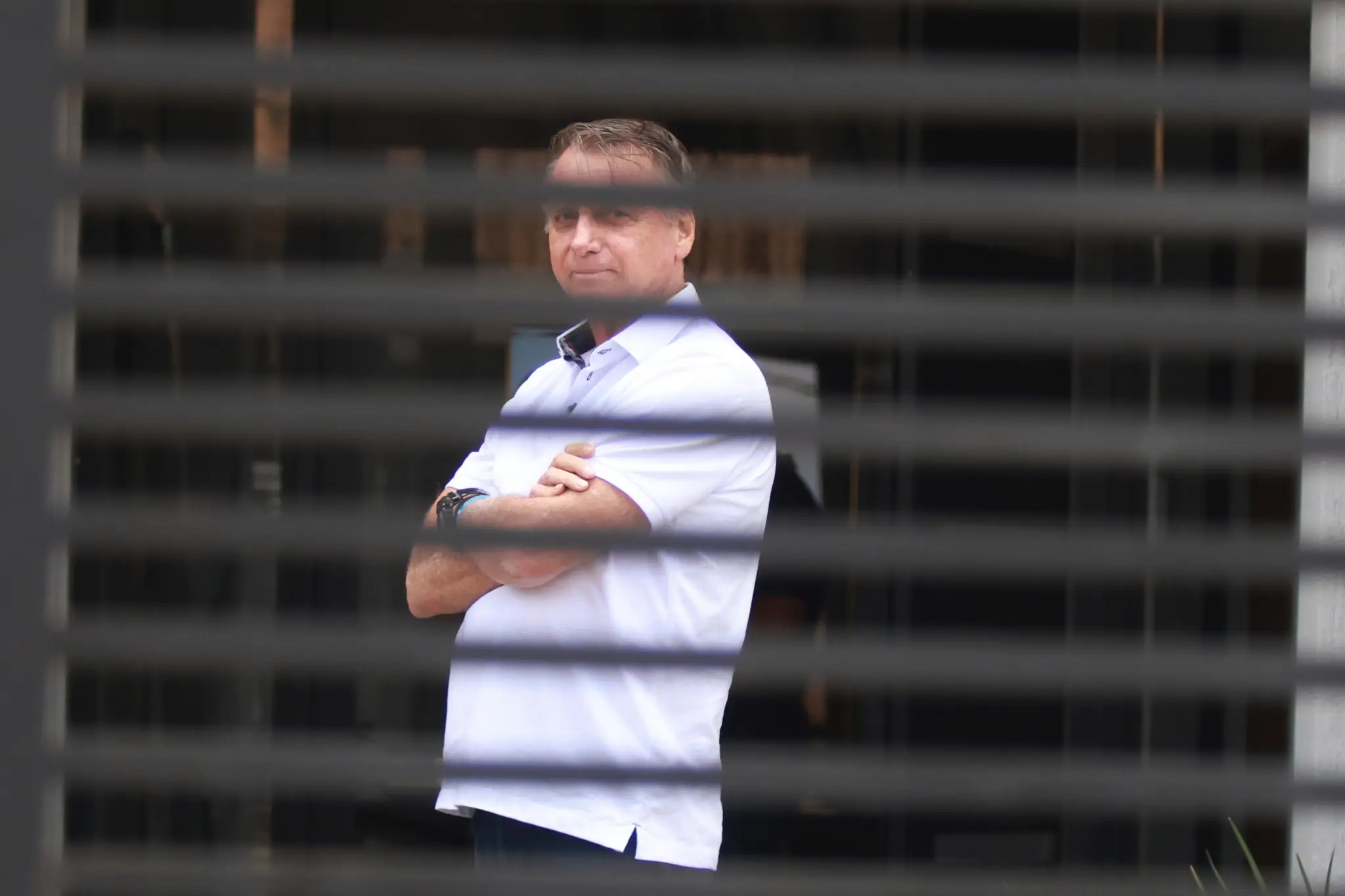 Bývalý brazílsky prezident Jair Bolsonaro stojí pri vchode do svojho domu, kde je v domácom väzení v Brazílii.