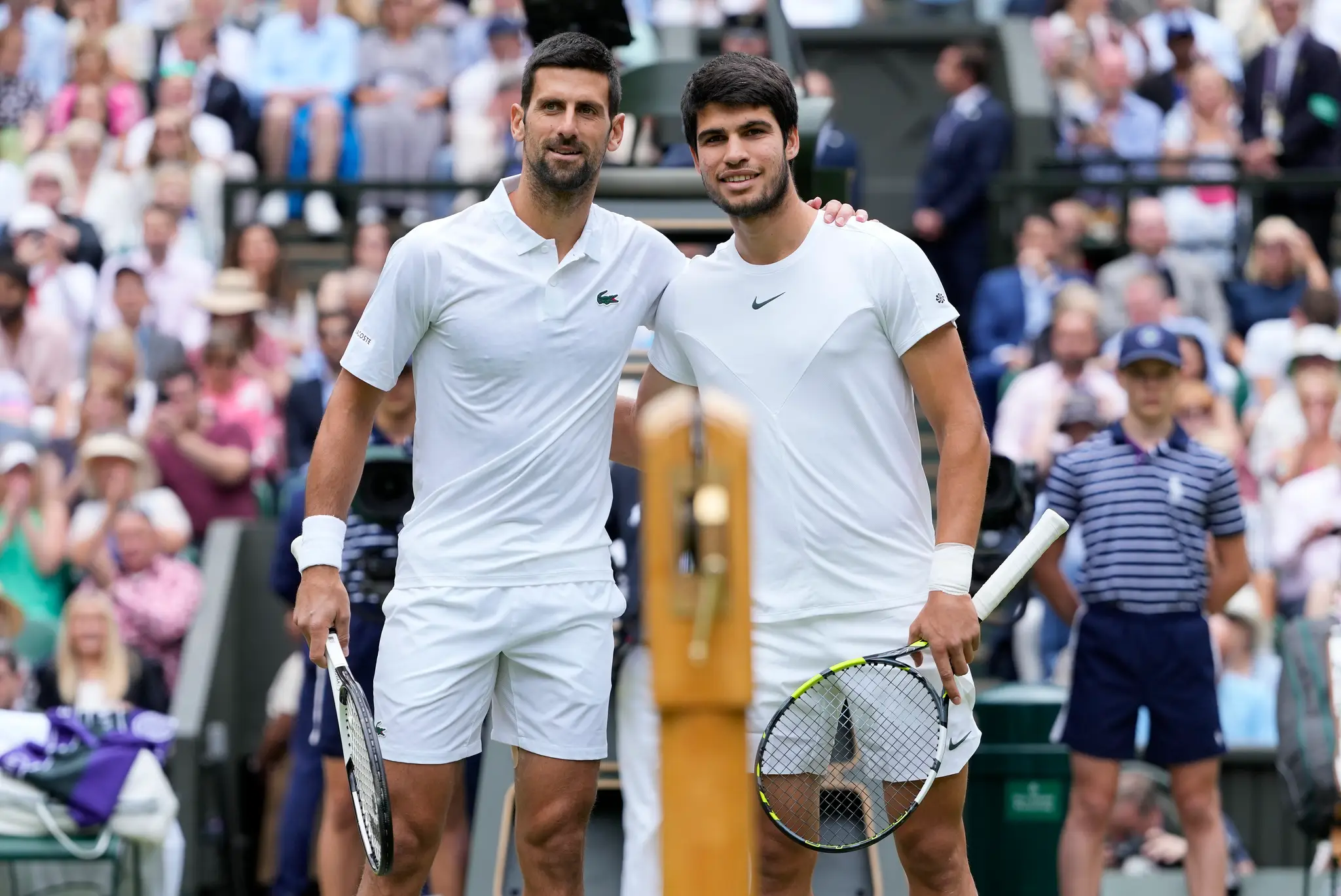 Novak Djokovič (vľavo) a Španiel Carlos Alcaraz pózujú pri sieti pred začiatkom finále mužskej dvojhry na grandslamovom tenisovom turnaji Wimbledon