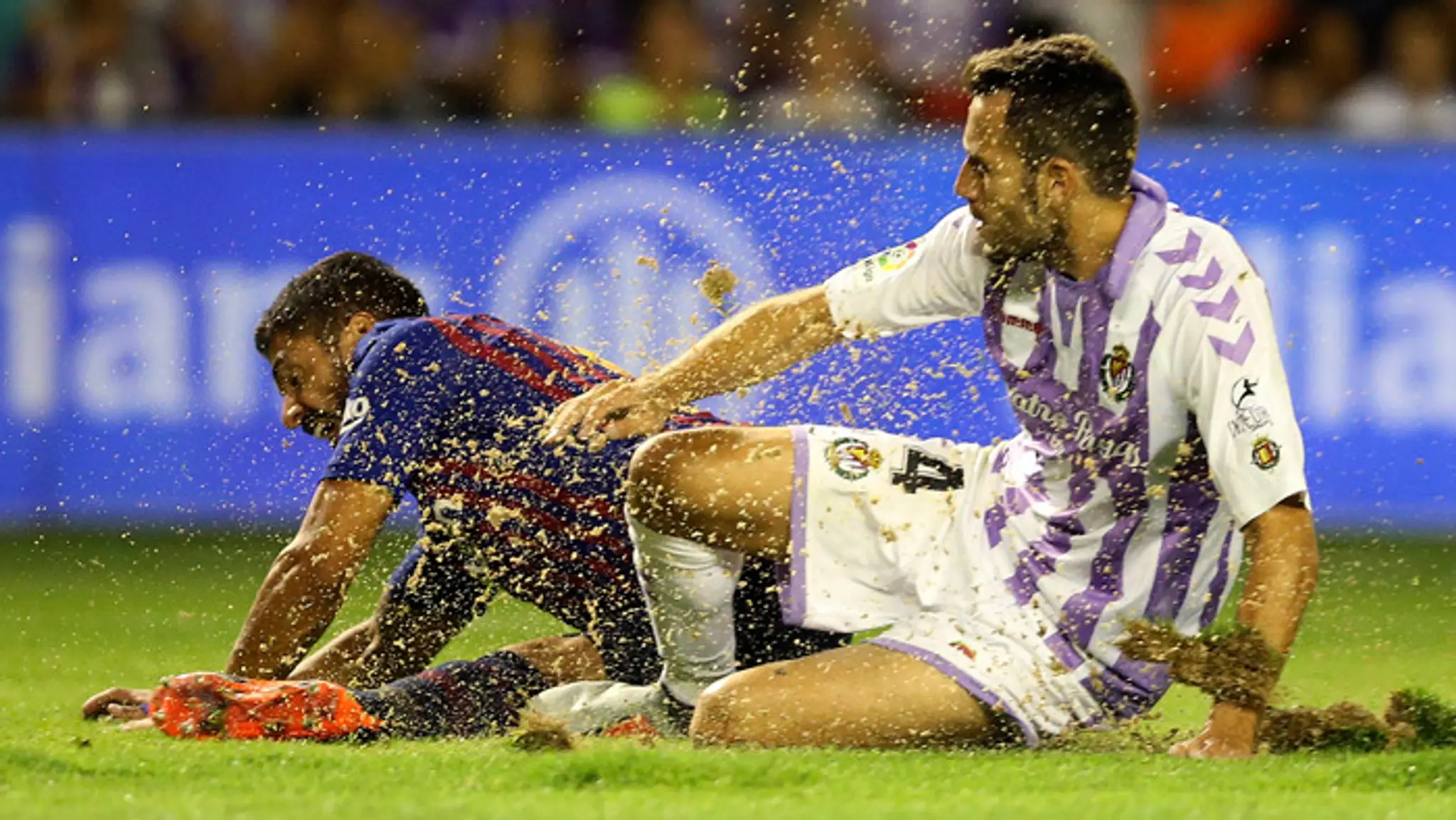 Luis Suarez (Barcelona) a hráč Valladolid Kiko Olivas, za ktorým vidno zlú kvalitu trávnika.