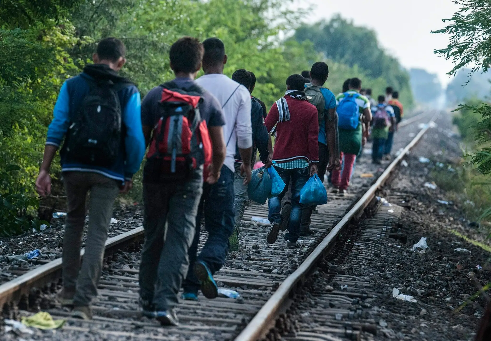 Utečenci prechádzajú po železničnej trati na maďarsko-srbských hraniciach