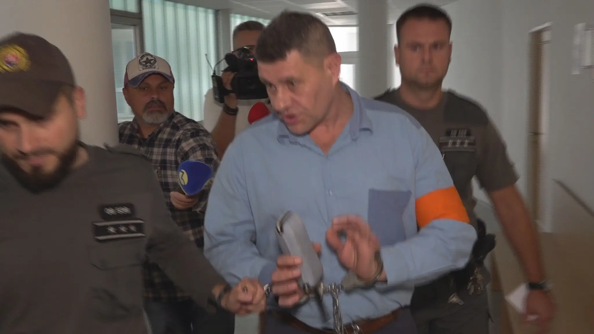 Muža, obžalovaného zo zabitia družky, privádzajú do súdnej siene. 