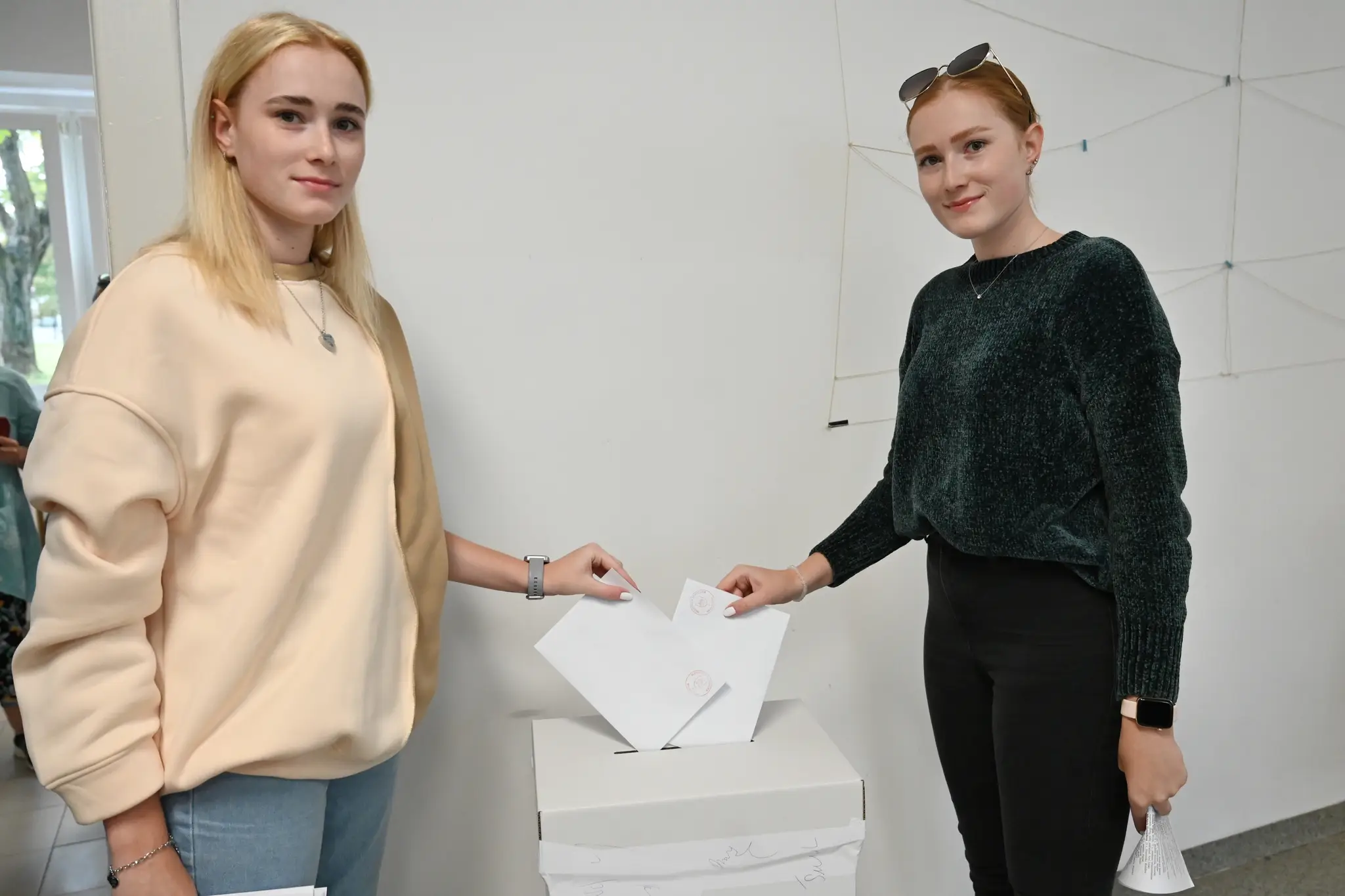Zľava prvovoličky Dominika a Karolína vhadzujú obálku s hlasovacím lístkom do volebnej schránky v Trnave.