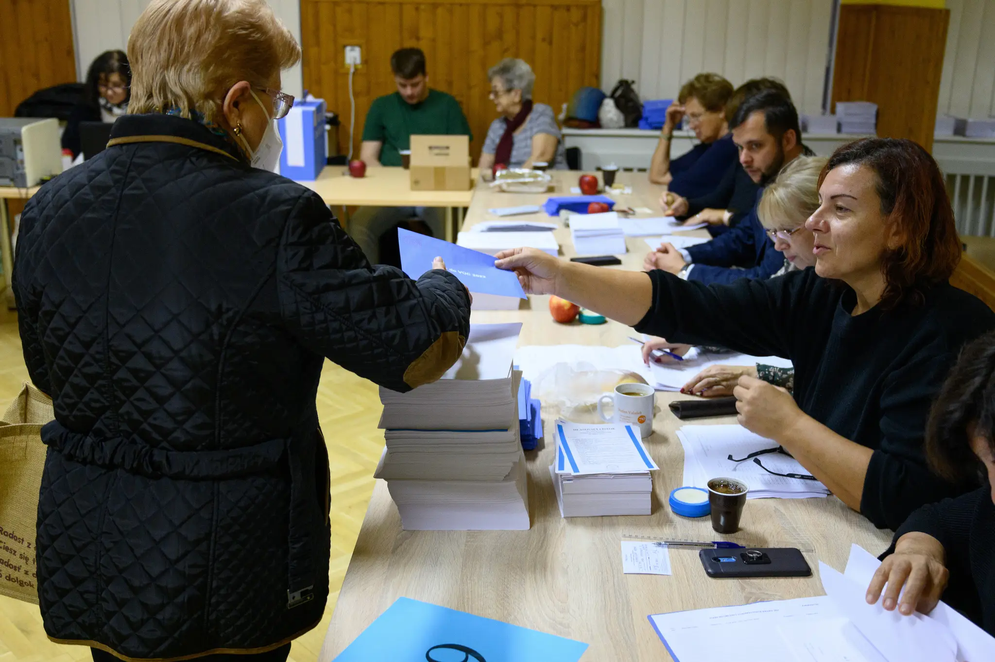 Na snímke volička si preberá obálku od členky volebnej komisie vo volebnej miestnosti v Centre voľného času Domino 29. októbra 2022 v Nitre.