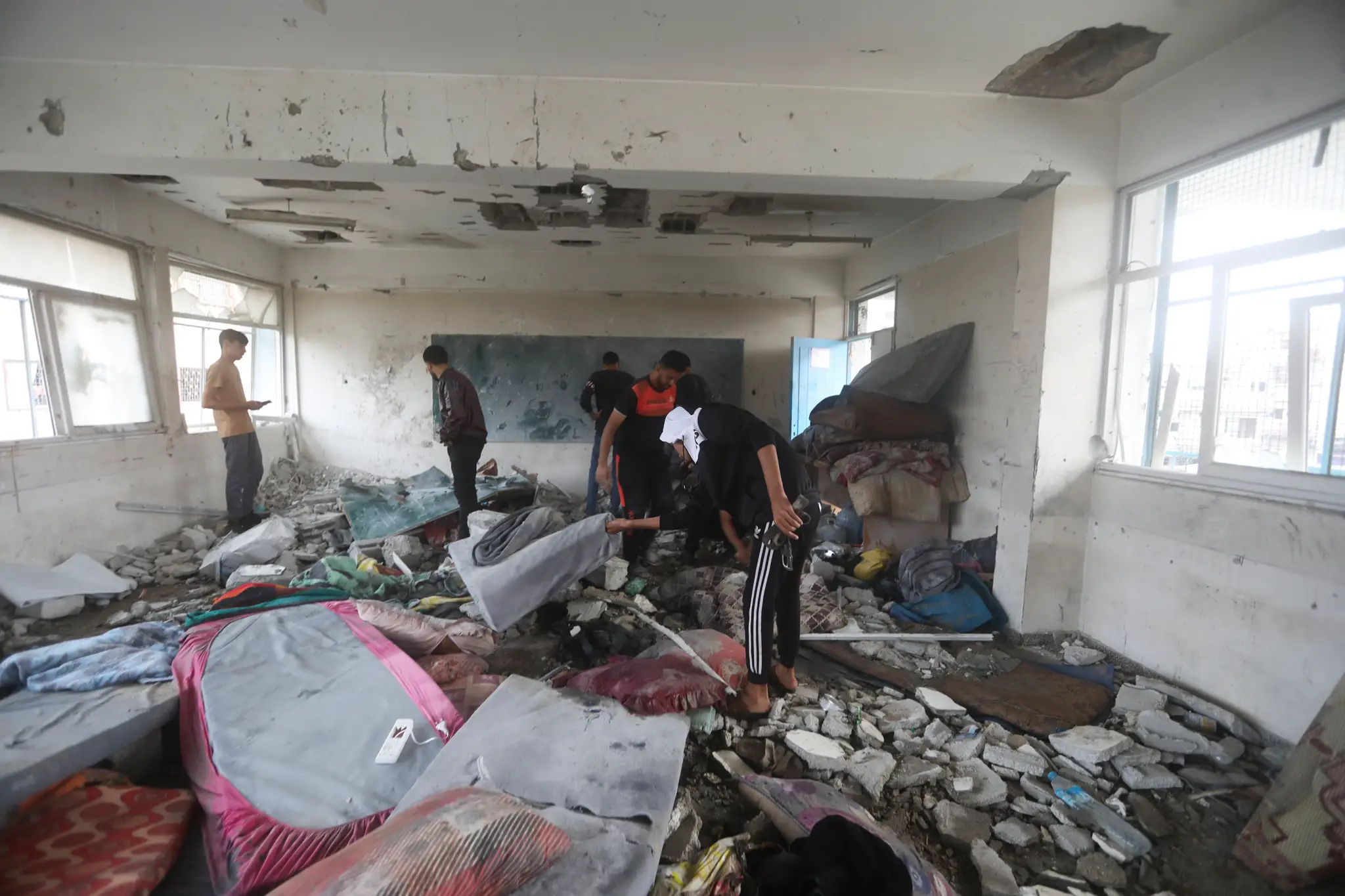 Palestínčania sa pozerajú na škody po izraelskom leteckom útoku na pásmo Gazy, kde bola zasiahnutá škola OSN.