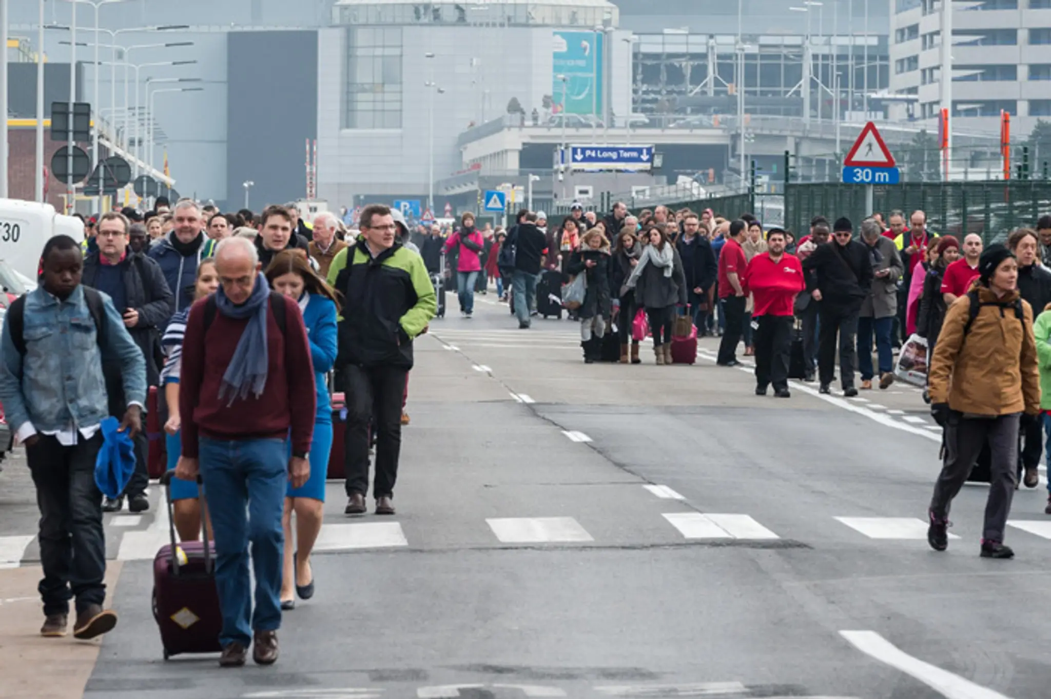 Ľudia odchádzajú z bruselského letiska Zaventem po explózii.
