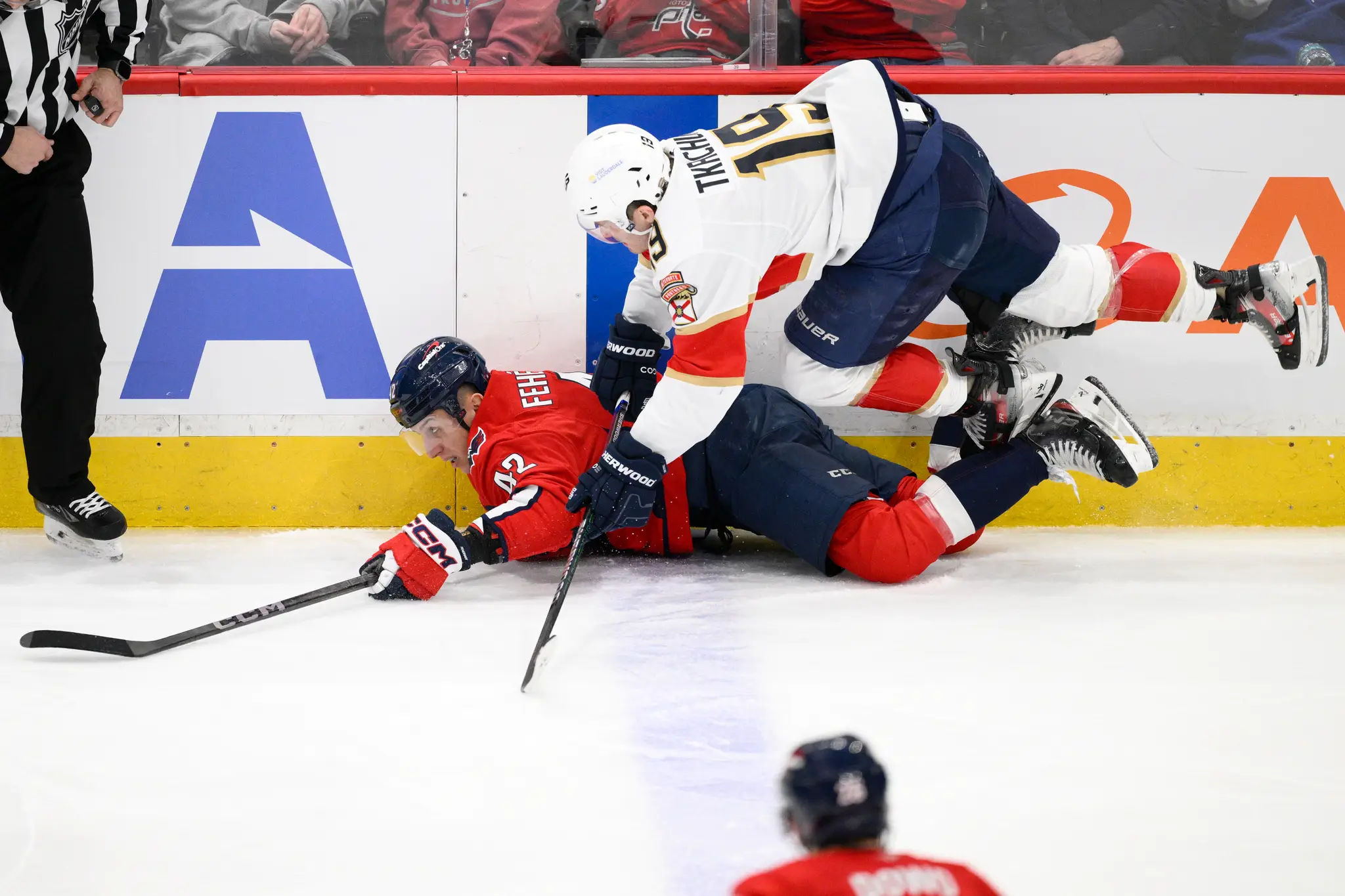 Slovenský hokejista v drese Washingtonu Capitals Martin Fehérváry (42) a hráč Floridy Matthew Tkachuk (19) bojujú o puk pri mantineli.