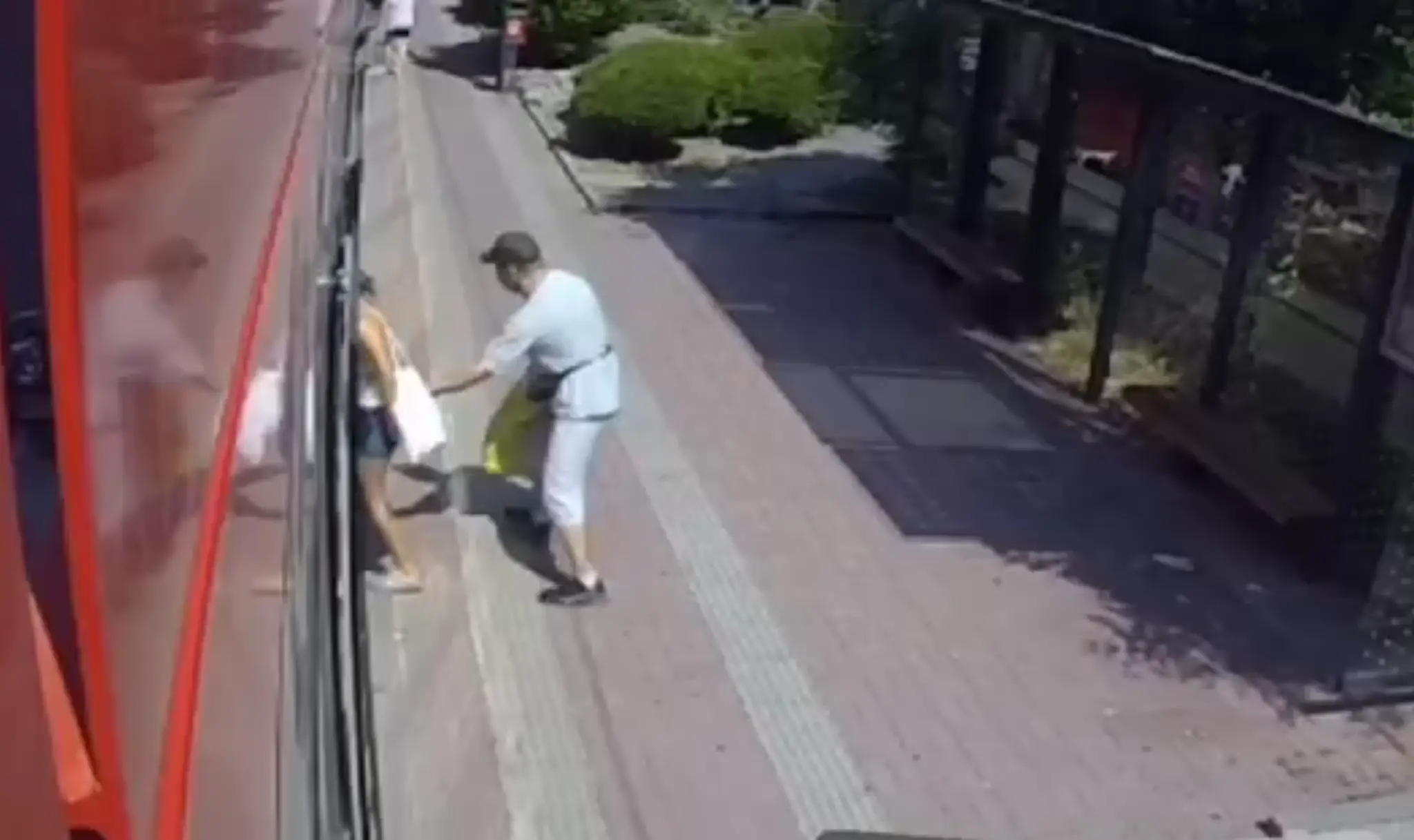 Muž chytá cestujúci pri nastupovaní do električky za zadnú časť tela.