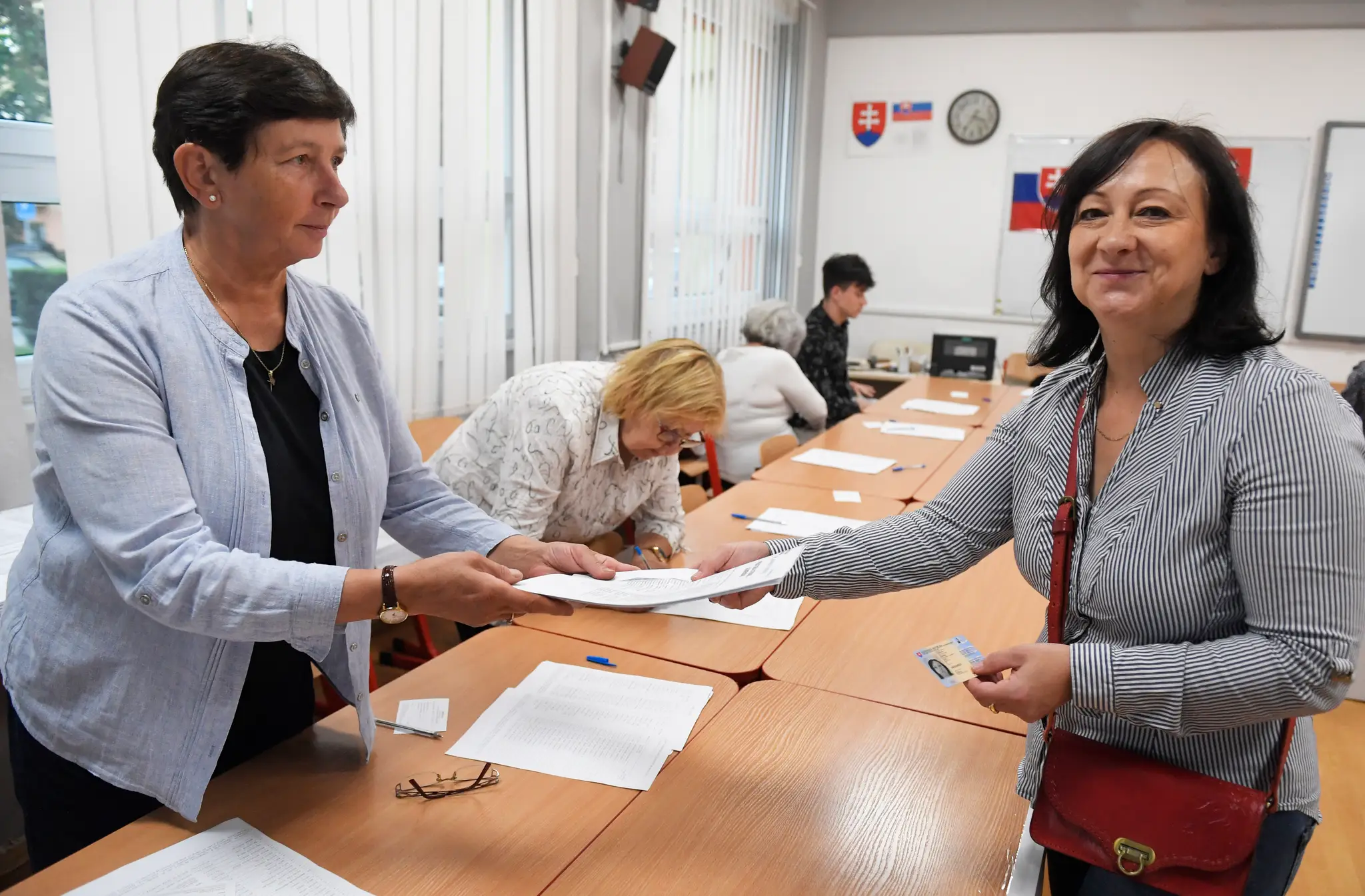 Volička sa preukazuje občianskym preukazom členke okrskovej volebnej komisie vo volebnej miestnosti v Košiciach.