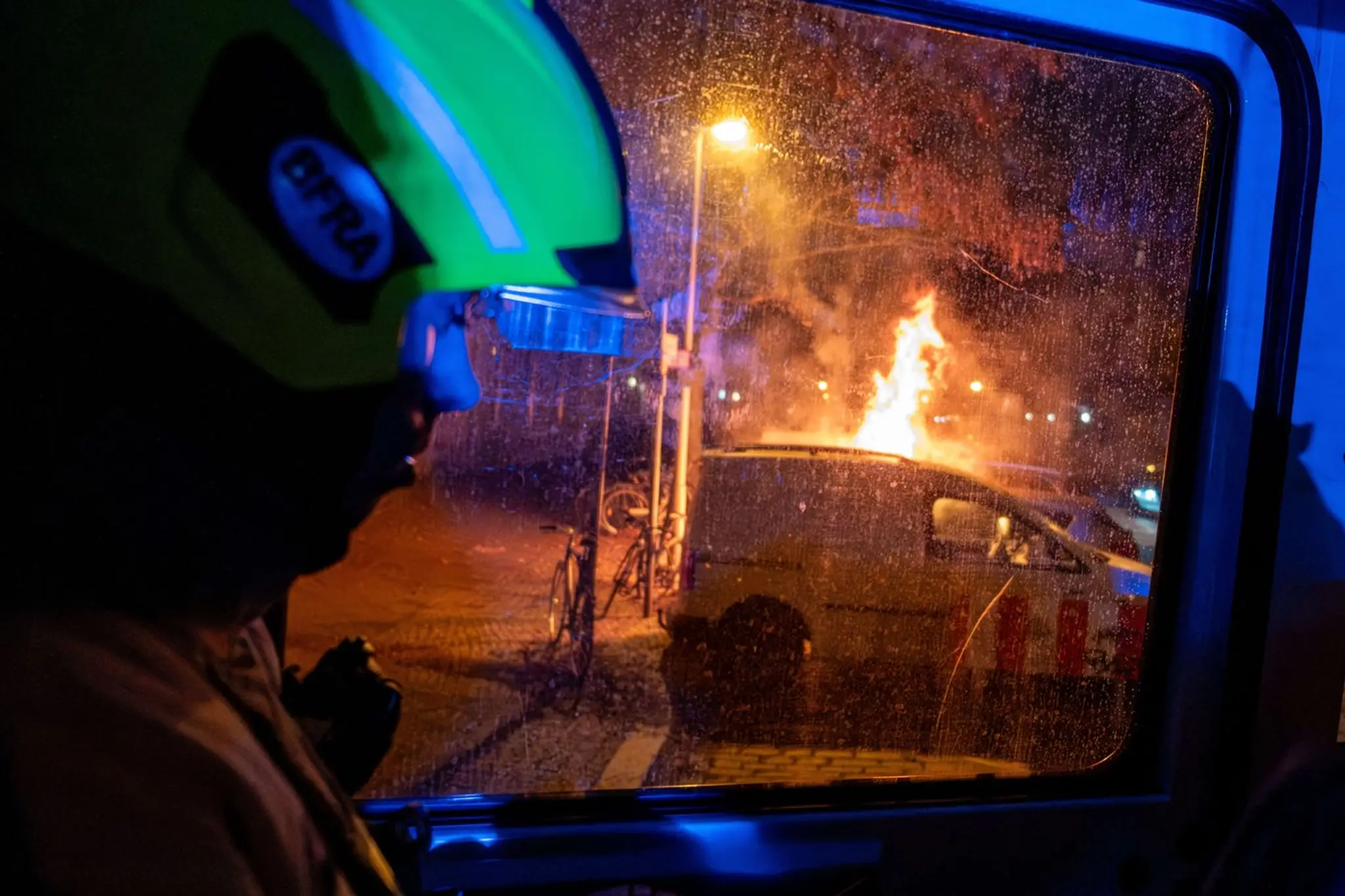 Na snímke hasič a horiace auto.