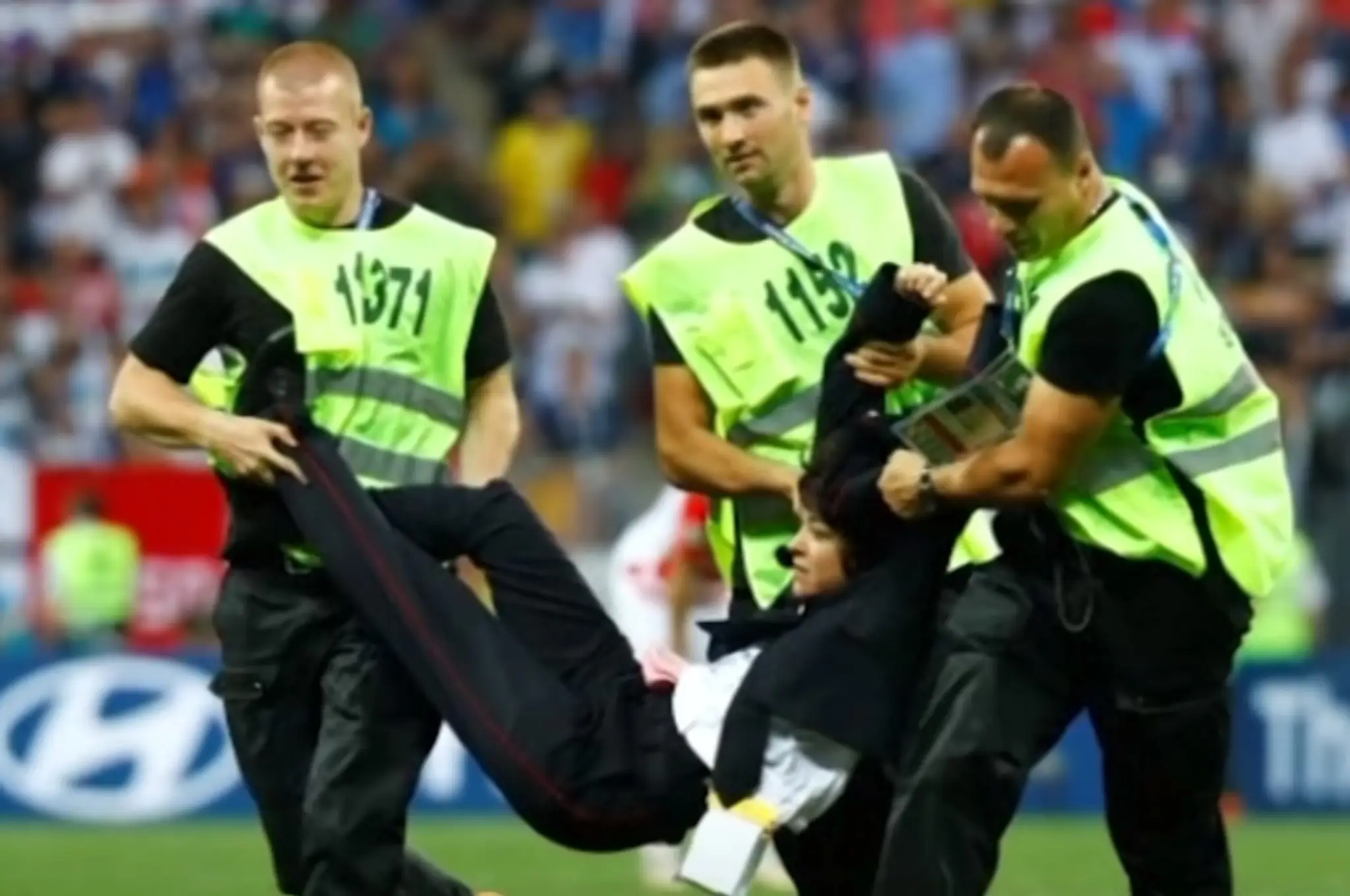 Usporiadateľská služba odnáša z ihriska aktivistku.