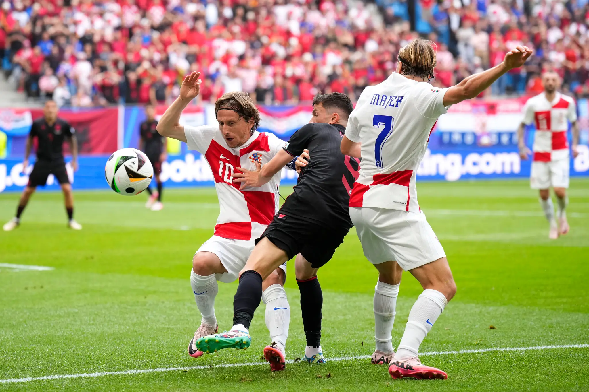 Chorvátski hráči Luka Modrič(vľavo) a Lovro Majer (vpravo) v súboji s Albáncom Jasirom Asanim (uprostred).