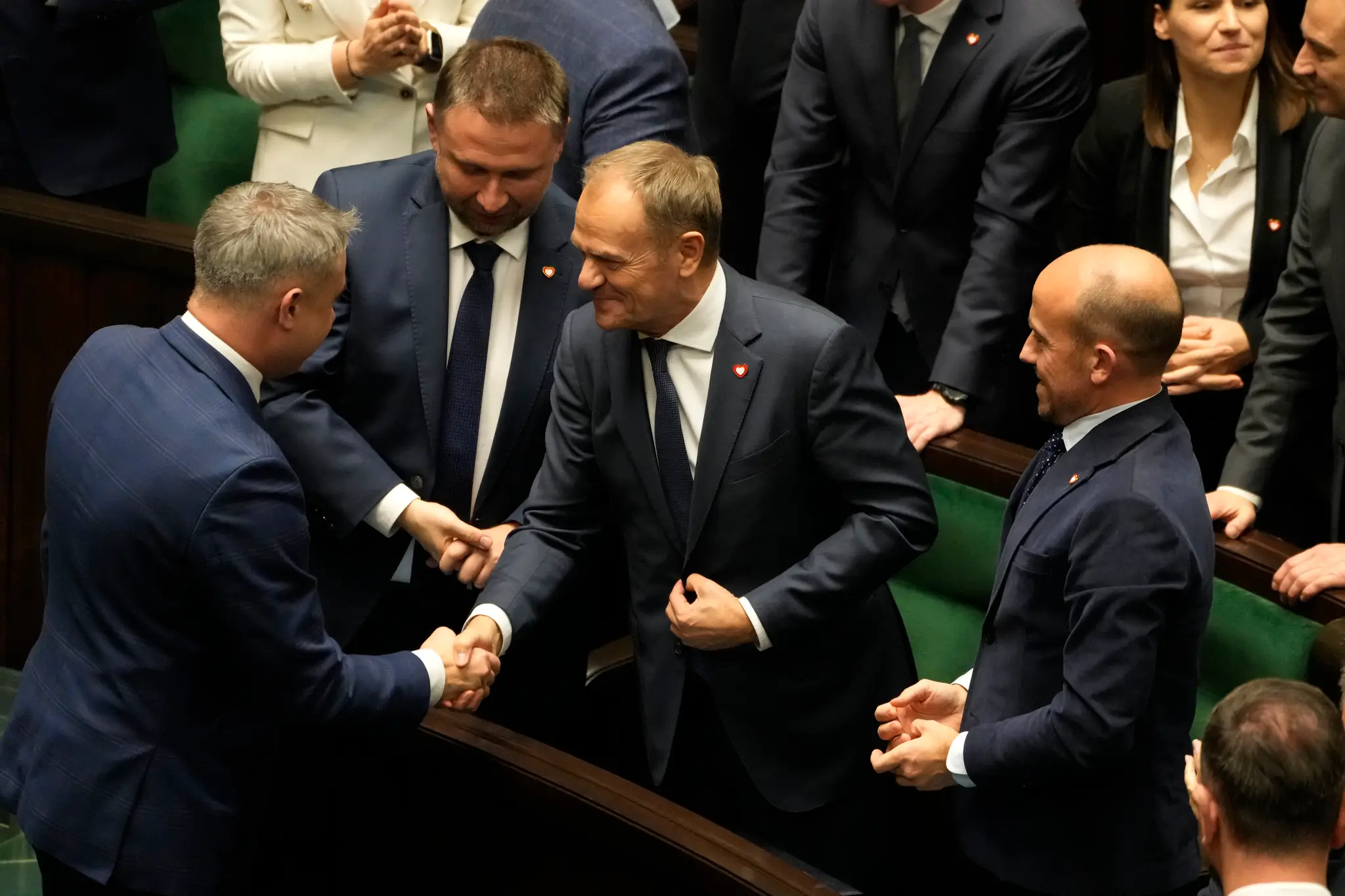 Poľský dezignovaný premiér Donald Tusk (uprostred) prijíma gratulácie od zákonodarcov po tom, čo jeho vláda získala dôveru dolnej komory parlamentu - Sejmu.