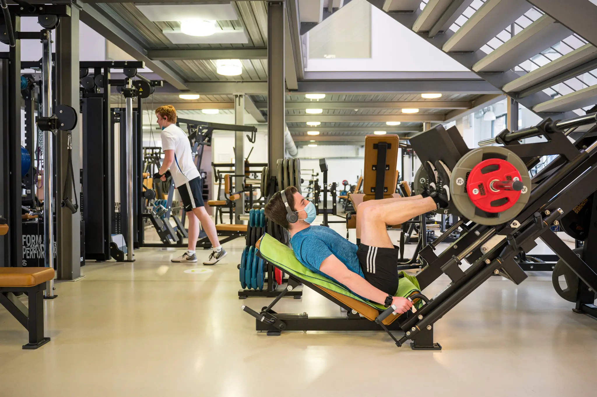 Ľudia cvičia v znovuotvorenom fitnescentre v nemeckom meste Saarbrücken.