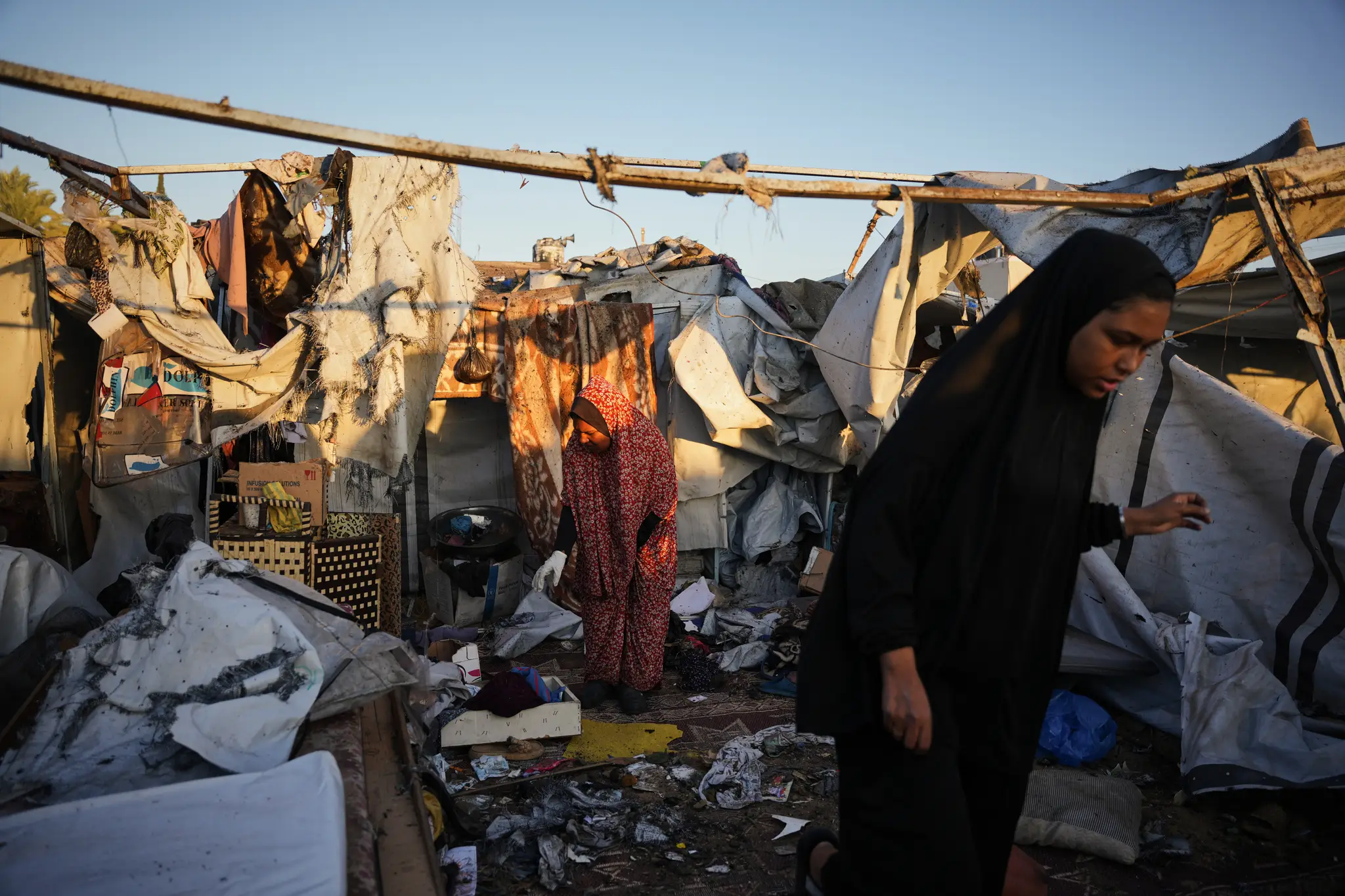 Na snímke vysídlené Palestínčanky si prezerajú materiálne škody po útoku izraelskej armády na utečenecký tábor v meste Dajr al-Balah v Pásme Gazy.
