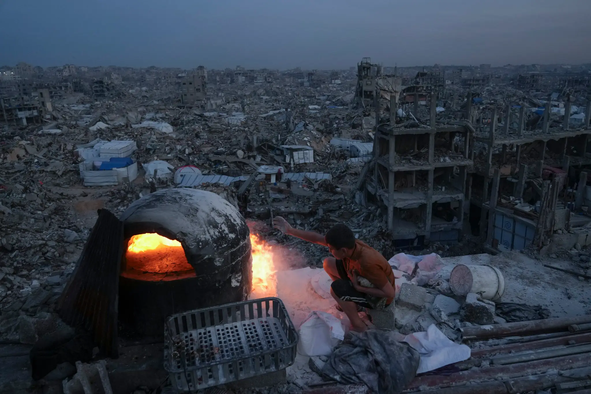 Palestínčania varia na streche svojho domu zničeného vzdušnou a pozemnou ofenzívou izraelskej armády v Pásme Gazy.