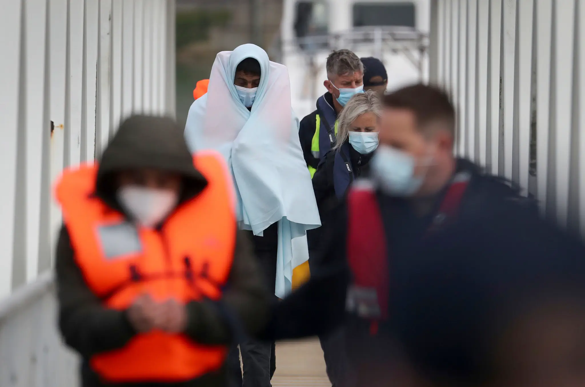 Skupina migrantov je eskortovaná policajtmi do prístavu v anglickom meste Dover.