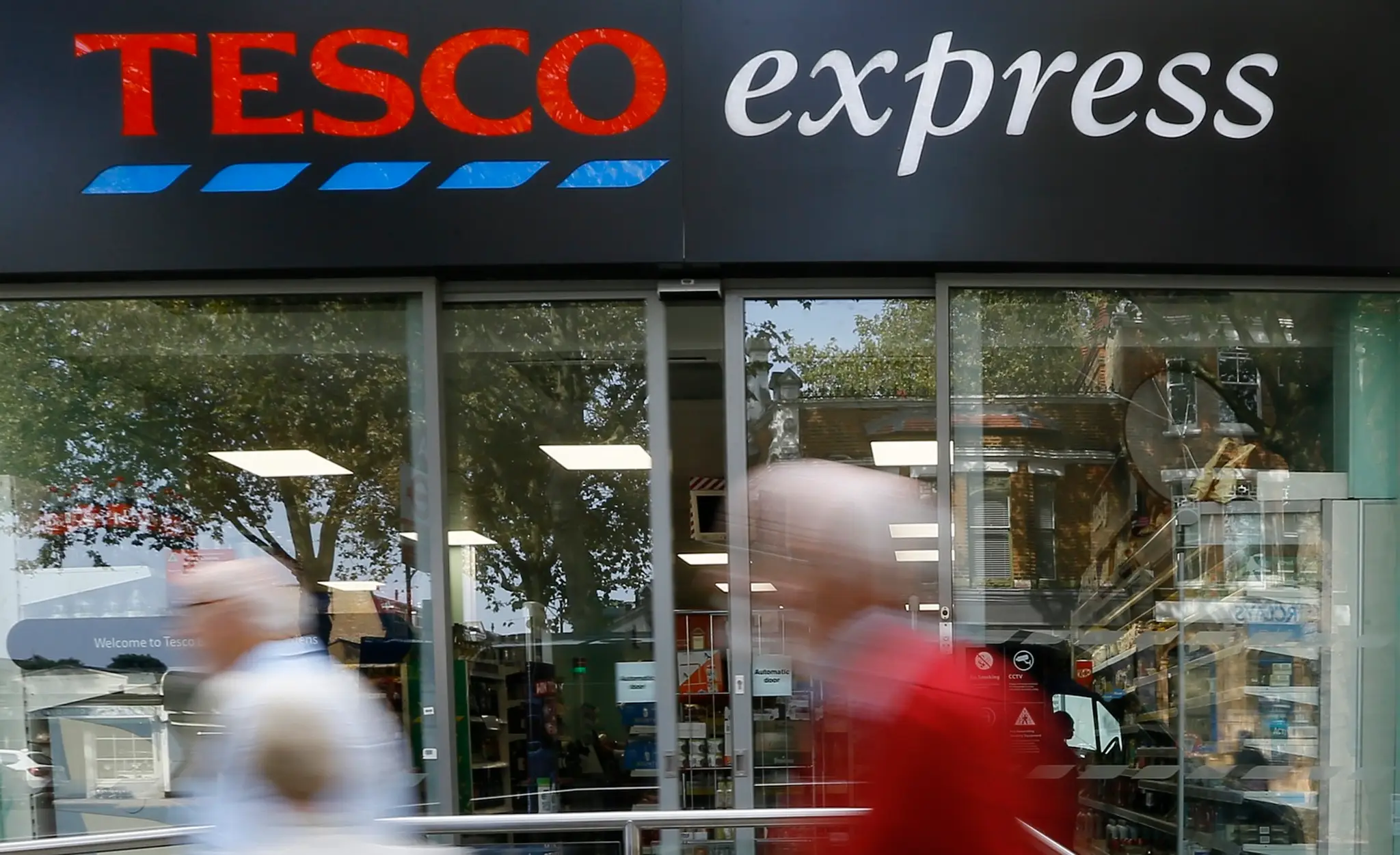 Ľudia prechádzajú okolo obchodu Tesco express.