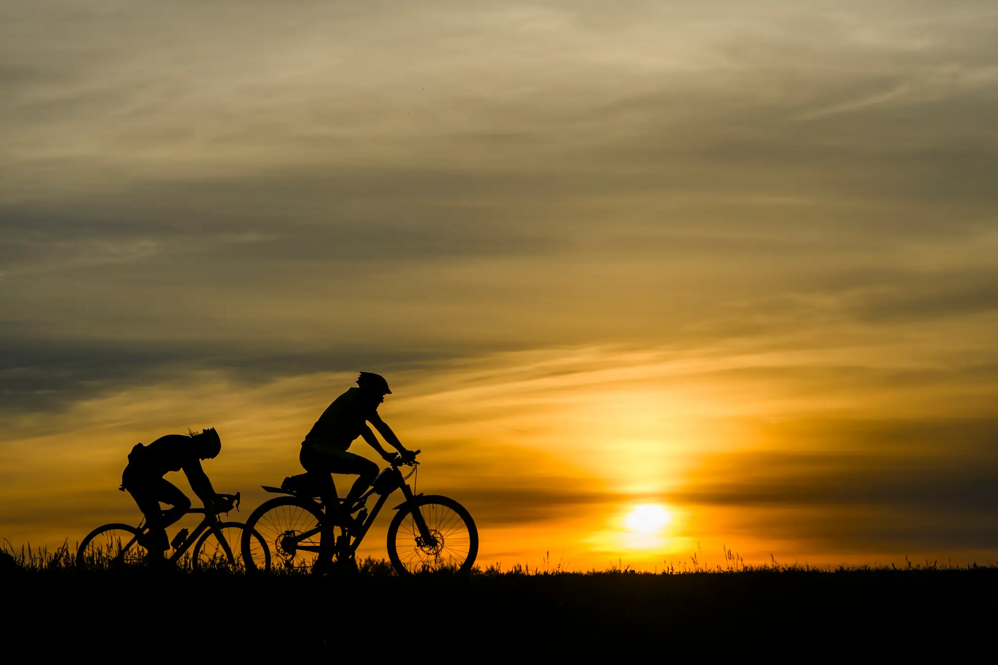 Na snímke cyklisti na hrádzi počas západu slnka