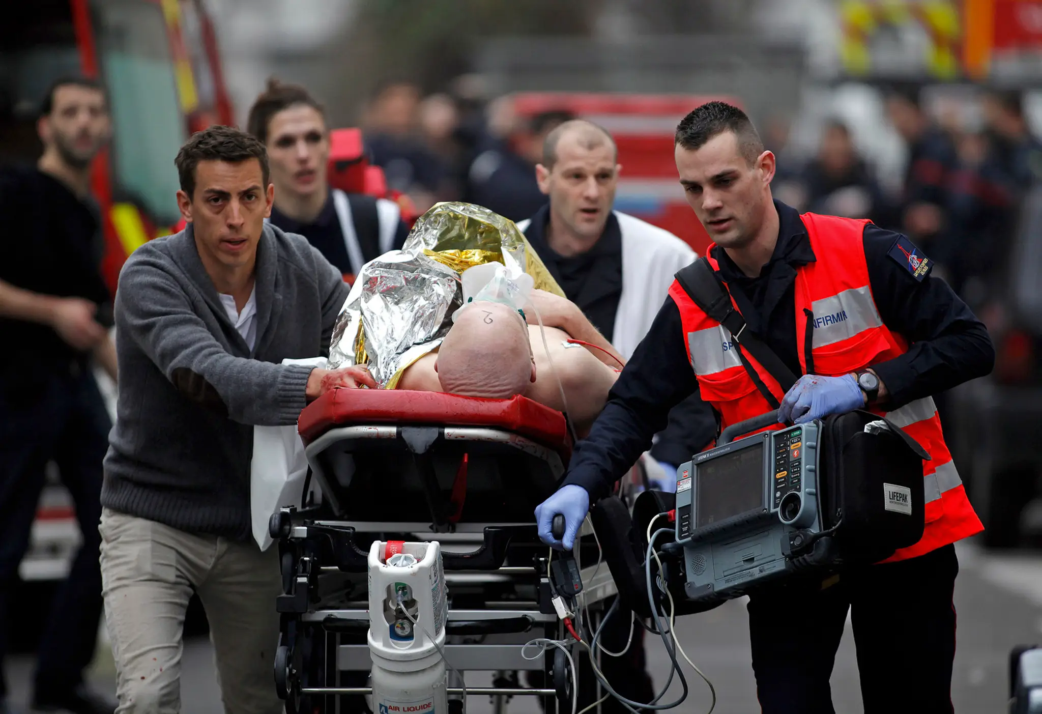 Zdravotníci evakuujú zranenú osobu z redakcie francúzskeho satirického týždenníka Charlie Hebdo 7. januára 