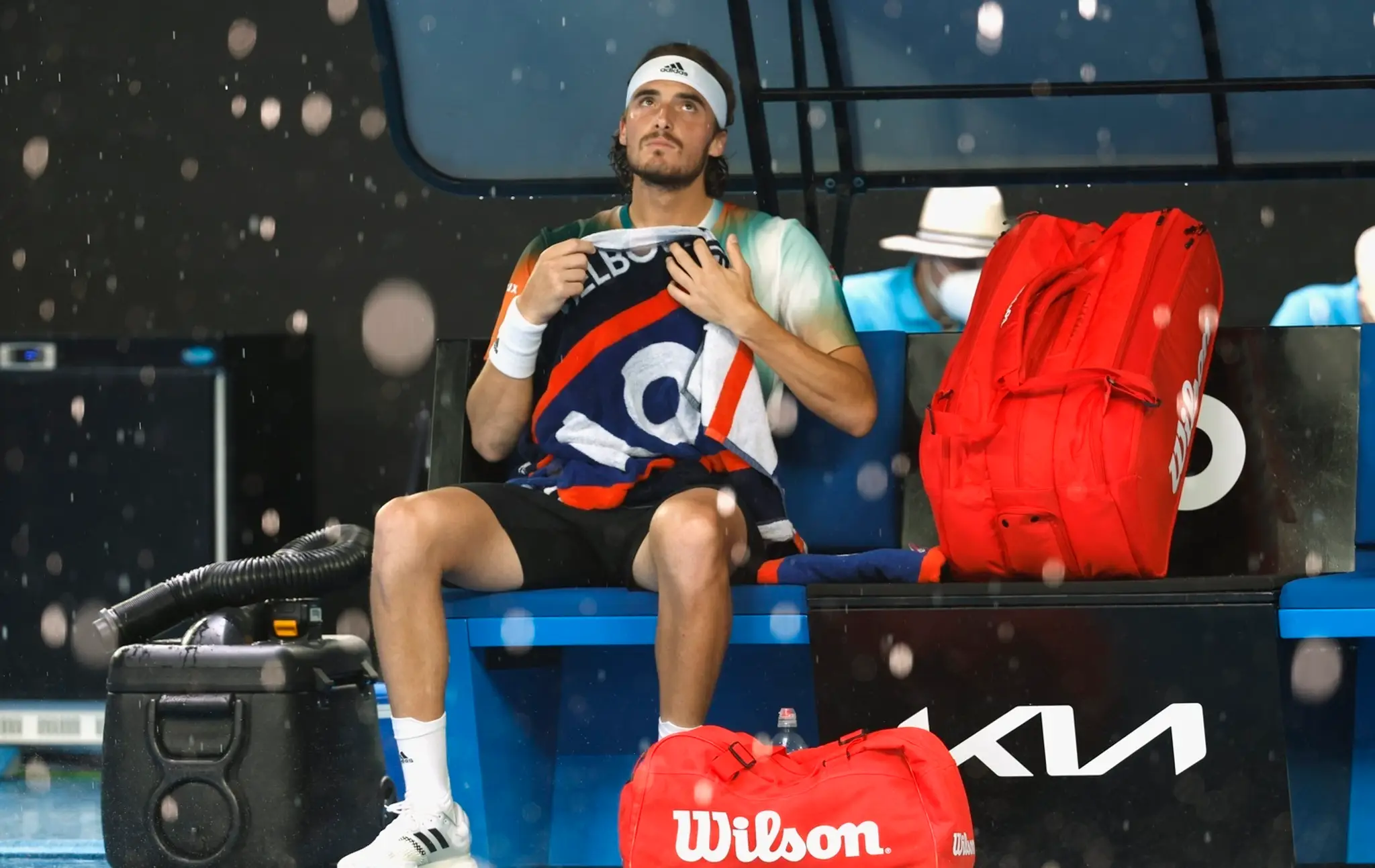Grécky tenista Stefanos Tsitsipas sedí na lavičke počas prerušenia zápasu kvôli dažďu vo štvrťfinále mužskej dvojhry.